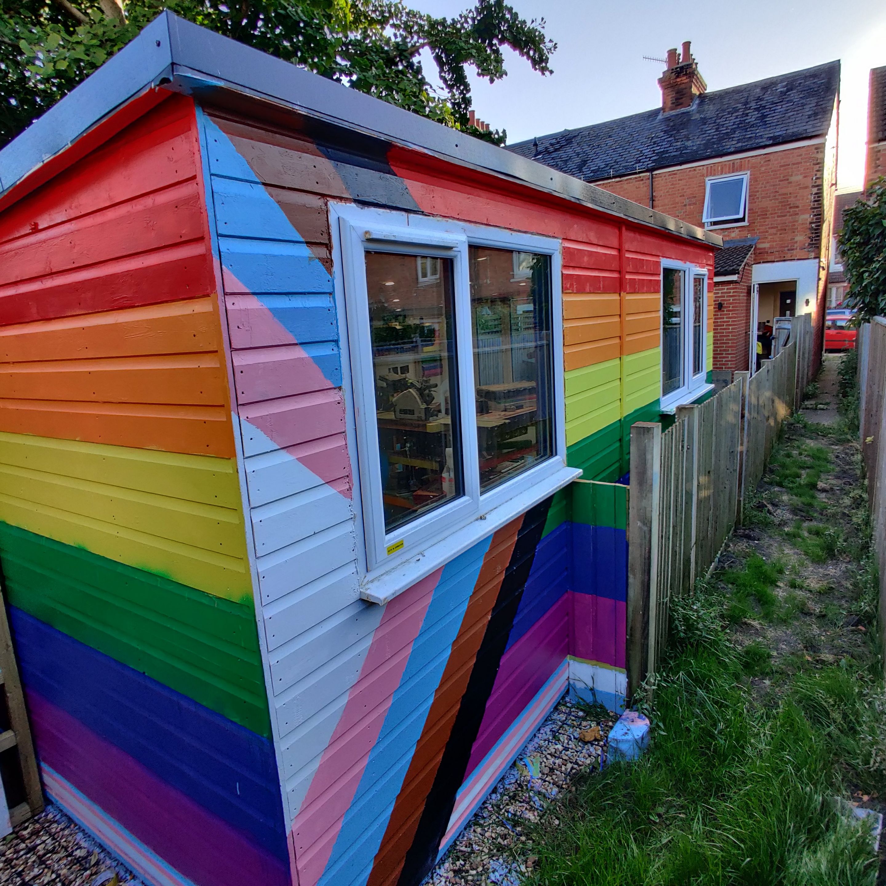 The Progress Pride Flag, painted on a wooden shed, 
The Shed features UPVC Triple Glazed Windows