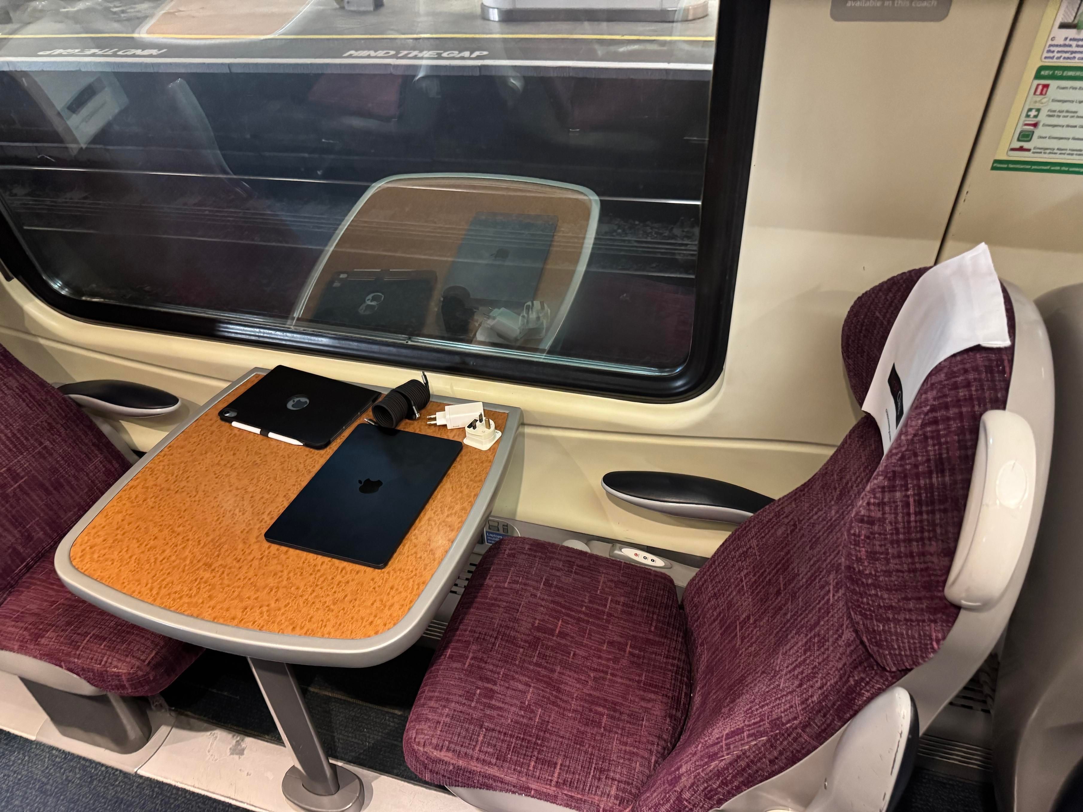 My seat for the trip on the solo side of the cabin. Showing my laptop, iPad, charger and cables on the table.