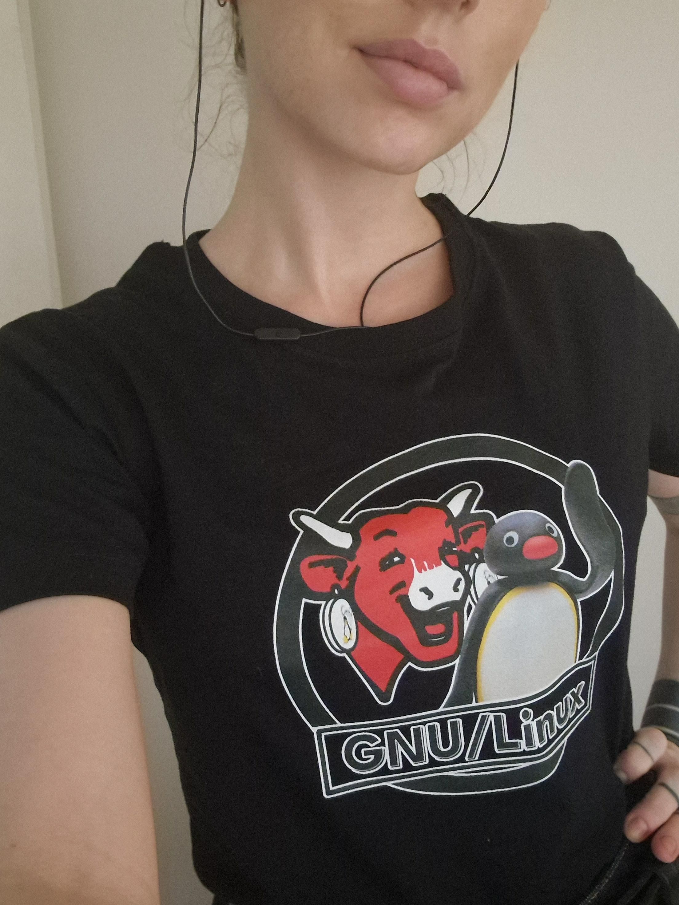 Selfie of me in a black tshirt. It has a gnu/ Linux logo on it except it's the laughing cow and pingu instead of the gnu and tux