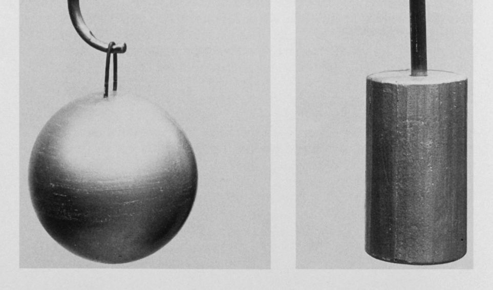 Closeup of 19th century oceanic sounding equipment, courtesy NOAA. On the left, a metal sphere that hangs precariously from a hook. On the right, a metal cylinder.