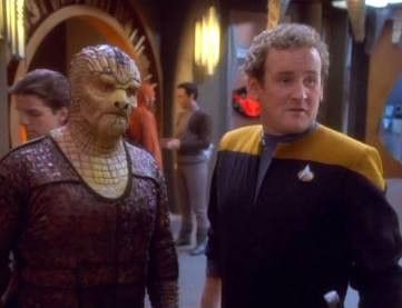 Tosk, an alien from the gamma quadrant, with reptilian features standing next to O’Brien. 