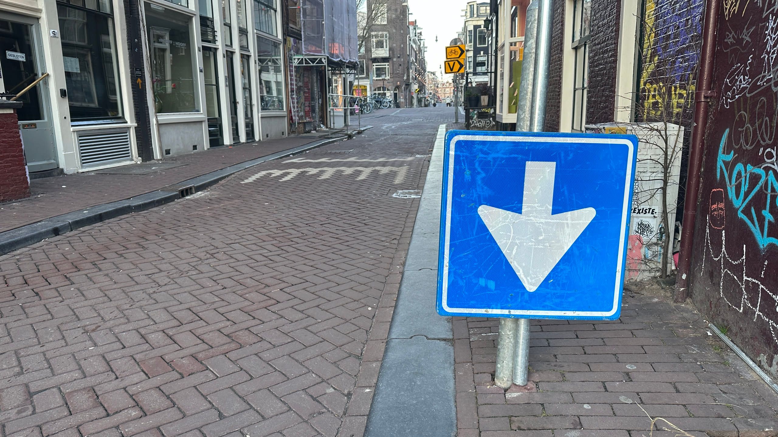 brick street with an upside down arrow on a blue sign