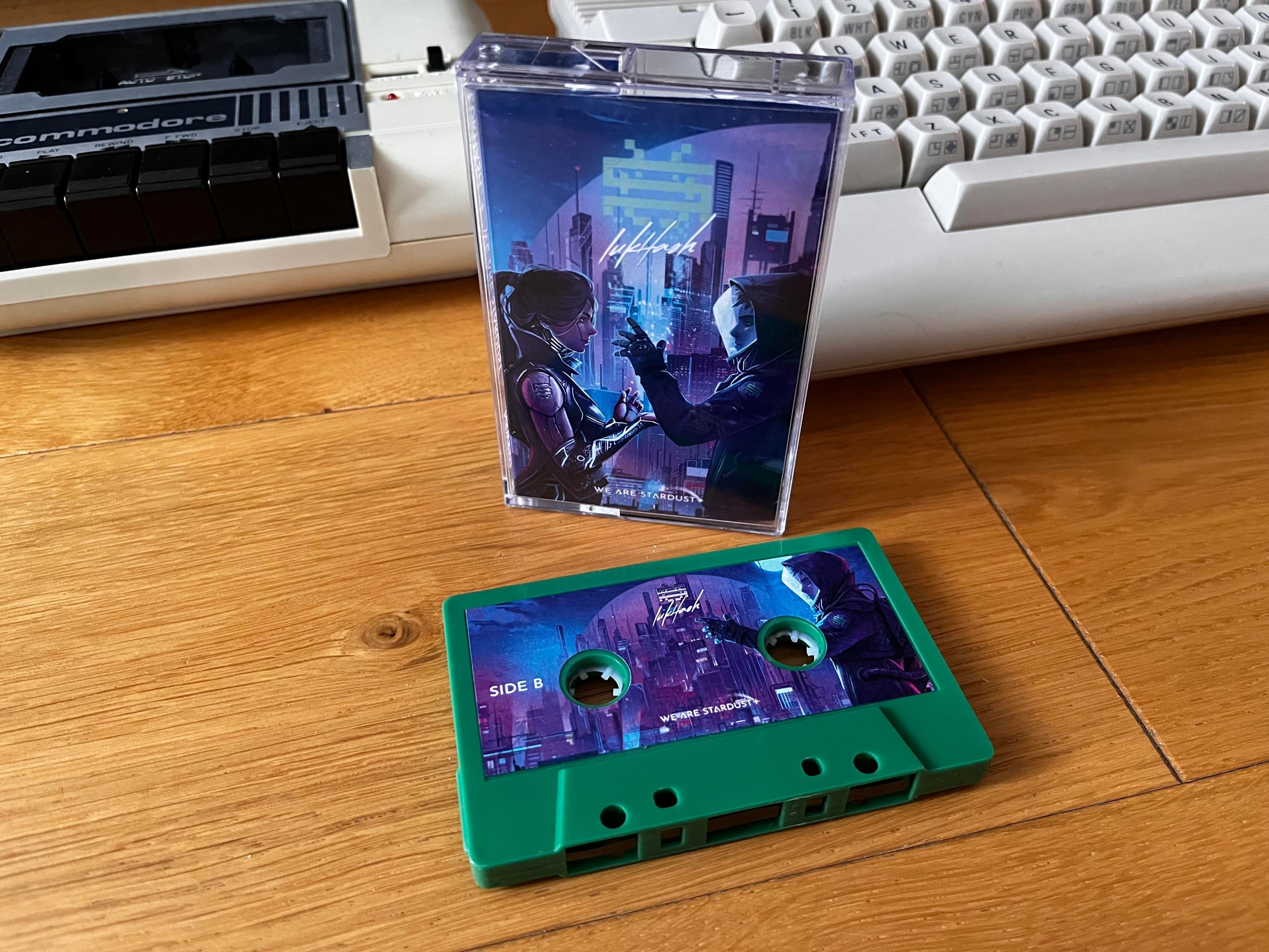 Cassette in green color with full printed sides. The case with the j-card is behind it. All in front of a C64C and 1530 datasette