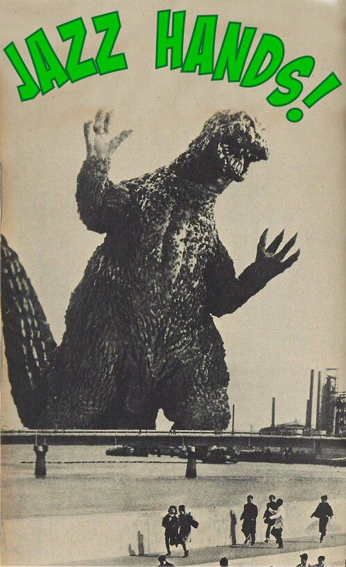 A sepia toned screen shot from a Godzilla film featuring Big G with is arms out and hands spread stomping into an industrial district. Excited lettering above his head reads "JAZZ HANDS!"