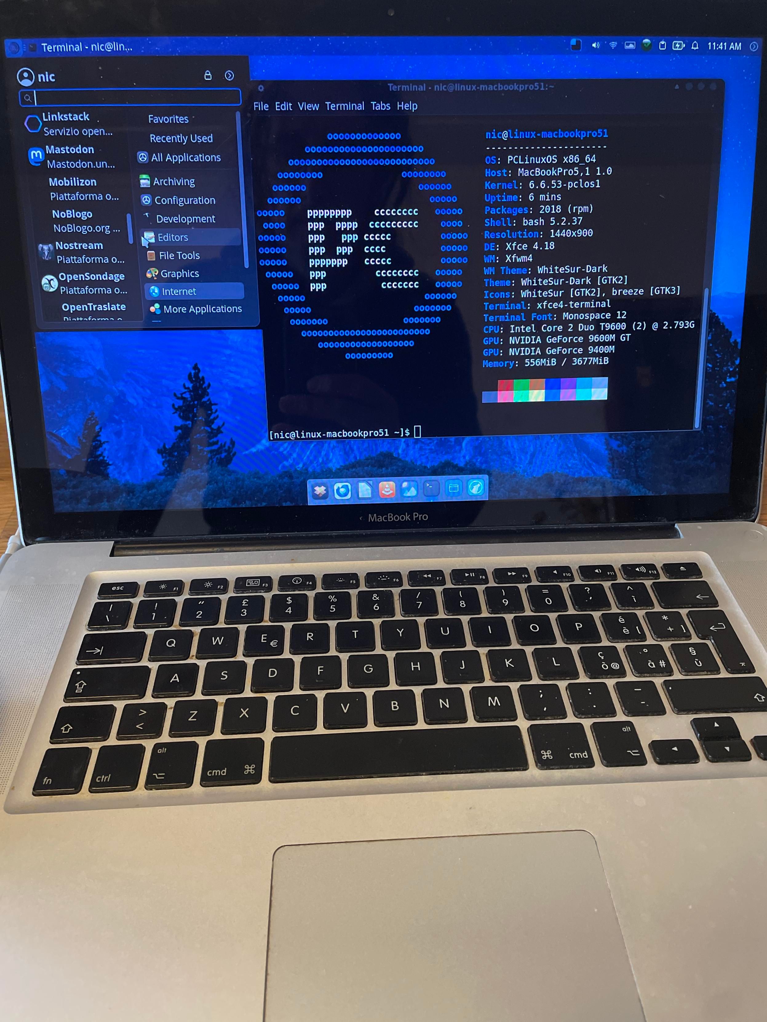 L'immagine mostra uno screenshot di un desktop di computer con una finestra di terminale in primo piano. Il terminale mostra un output di testo che include caratteri ripetuti ("o" e "c"). Sulla sinistra, una barra laterale mostra un menu di applicazioni suddiviso in categorie: "Favorites", "Recently Used", "All Applications" con sottocategorie come "Archiving", "Development", "Editors", "Graphics" e "Internet". Il desktop ha uno sfondo blu scuro con un logo in basso a sinistra. La barra superiore mostra informazioni sullo stato del sistema, tra cui l'ora (11:41 AM).

Alt-text: L'immagine mostra uno screenshot di un desktop di computer. Una finestra di terminale in primo piano mostra il testo "niclinux-macbookpro51", seguito da righe di output che consistono in una sequenza di "o" e "c". Una barra laterale a sinistra elenca diverse categorie di applicazioni, tra cui "Favorites", "Recently Used", "All Applications" e sottocategorie. Il desktop ha uno sfondo blu scuro. Sulla barra superiore è presente l'indicatore di ora "11:41 AM".