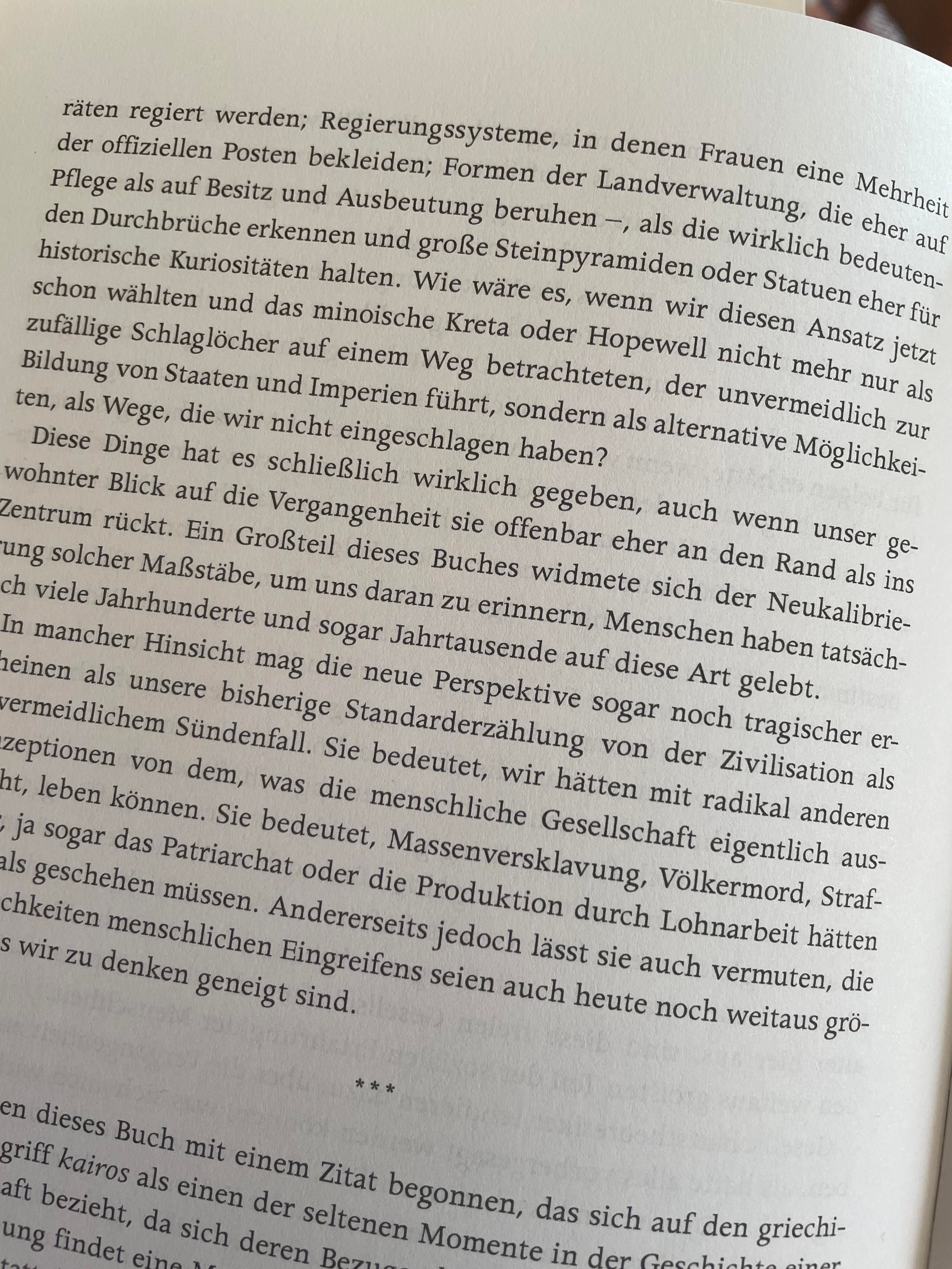 An open book page features a discussion in German on historical governance systems and societal structures, reflecting on alternative possibilities and the impact of perspective on civilization narratives.