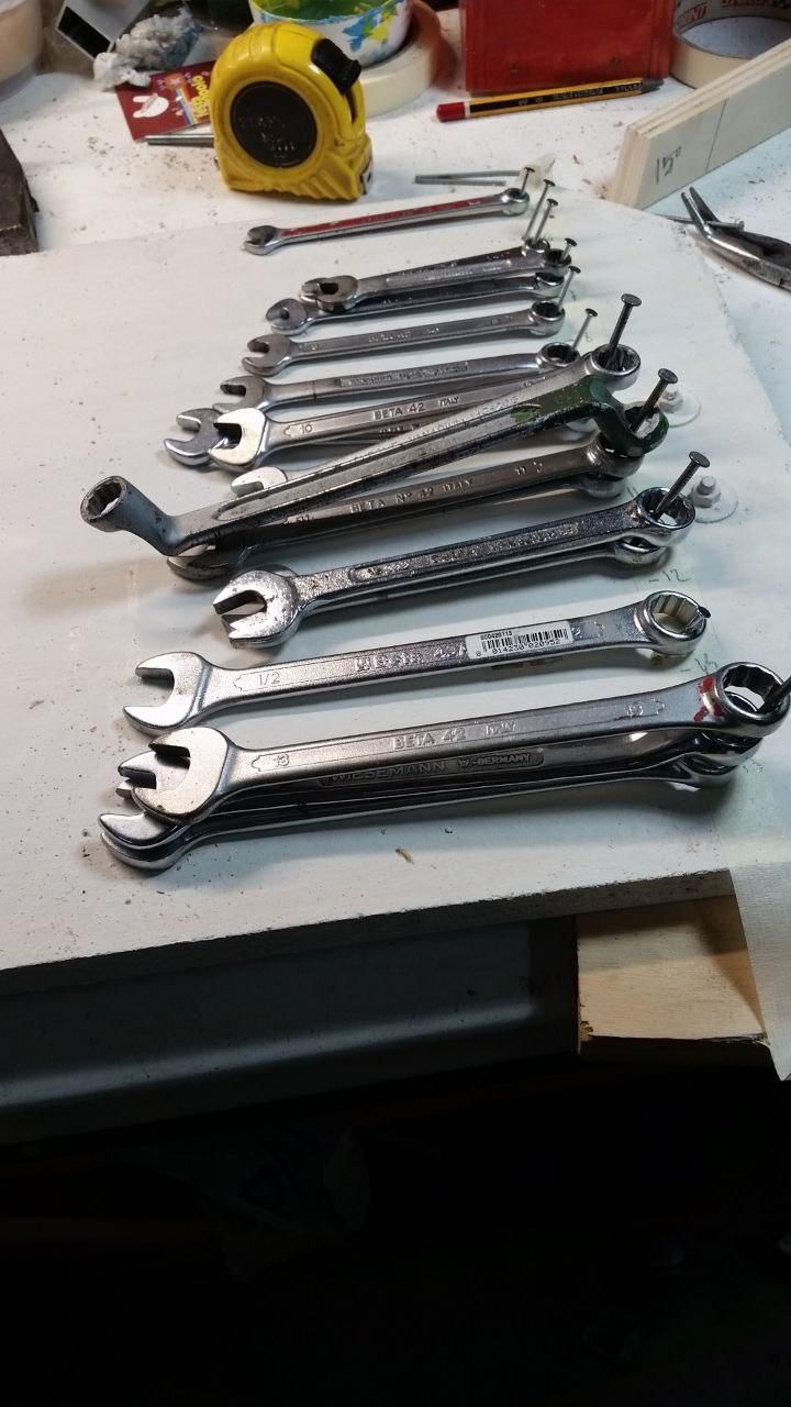 Fila di chiavi infilate su chiodi inclinati a 15°, dalla 5,5 mm alla 13 mm, più la ¼" e la ½".
Manca la 6 mm, ma è in giro da qualche parte e salterà fuori… prima o poi.