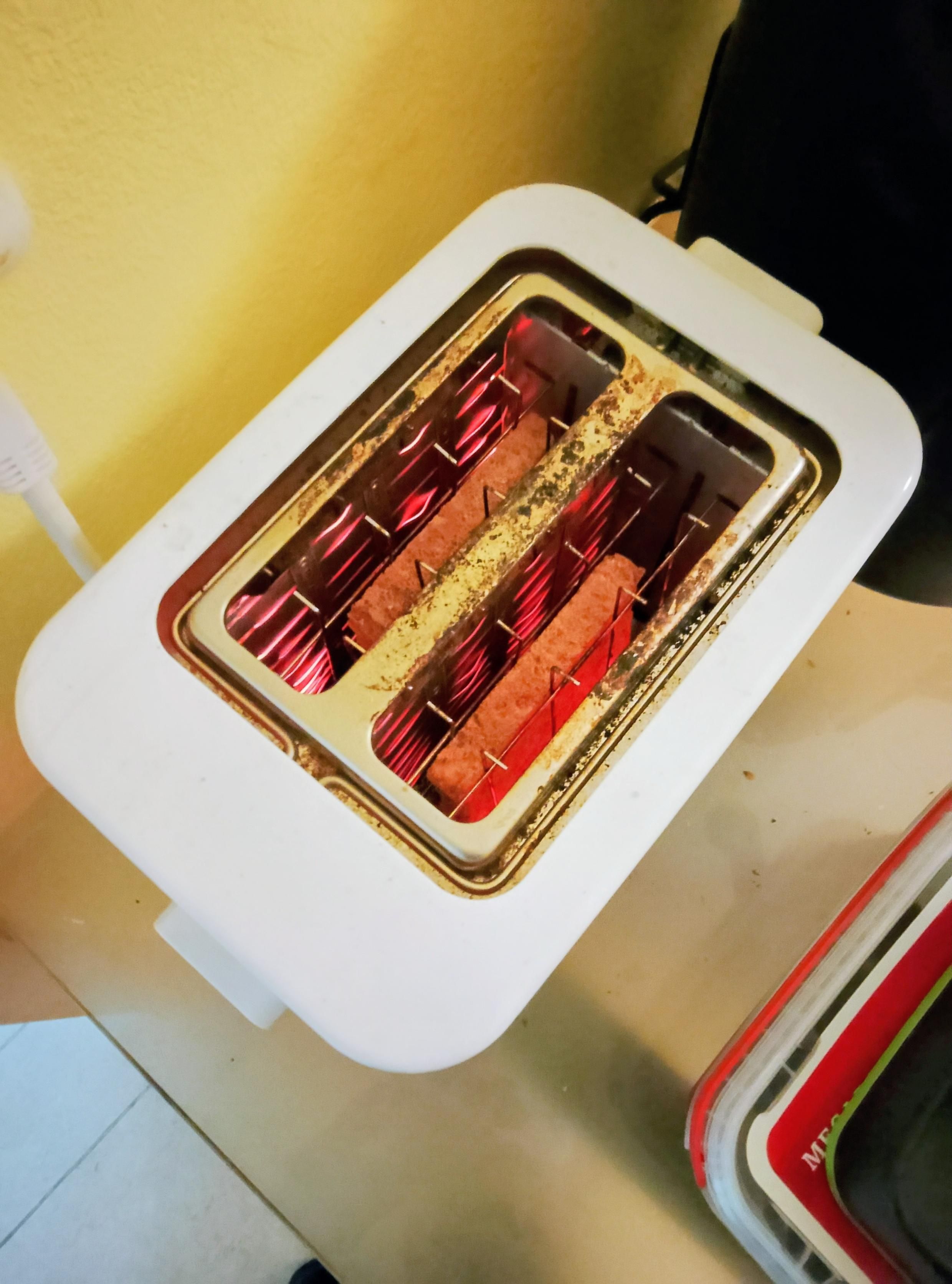 Filaments glow as toast toasts in the toaster, round side down. 