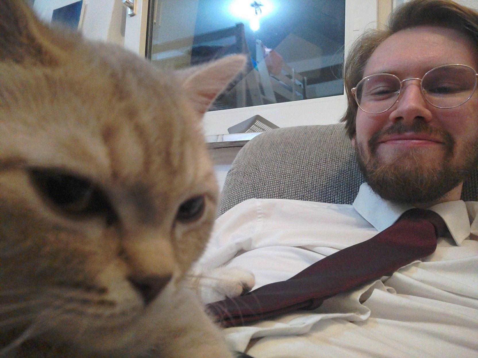 A picture of Erik Uden smiling at a kitten lying on top of him