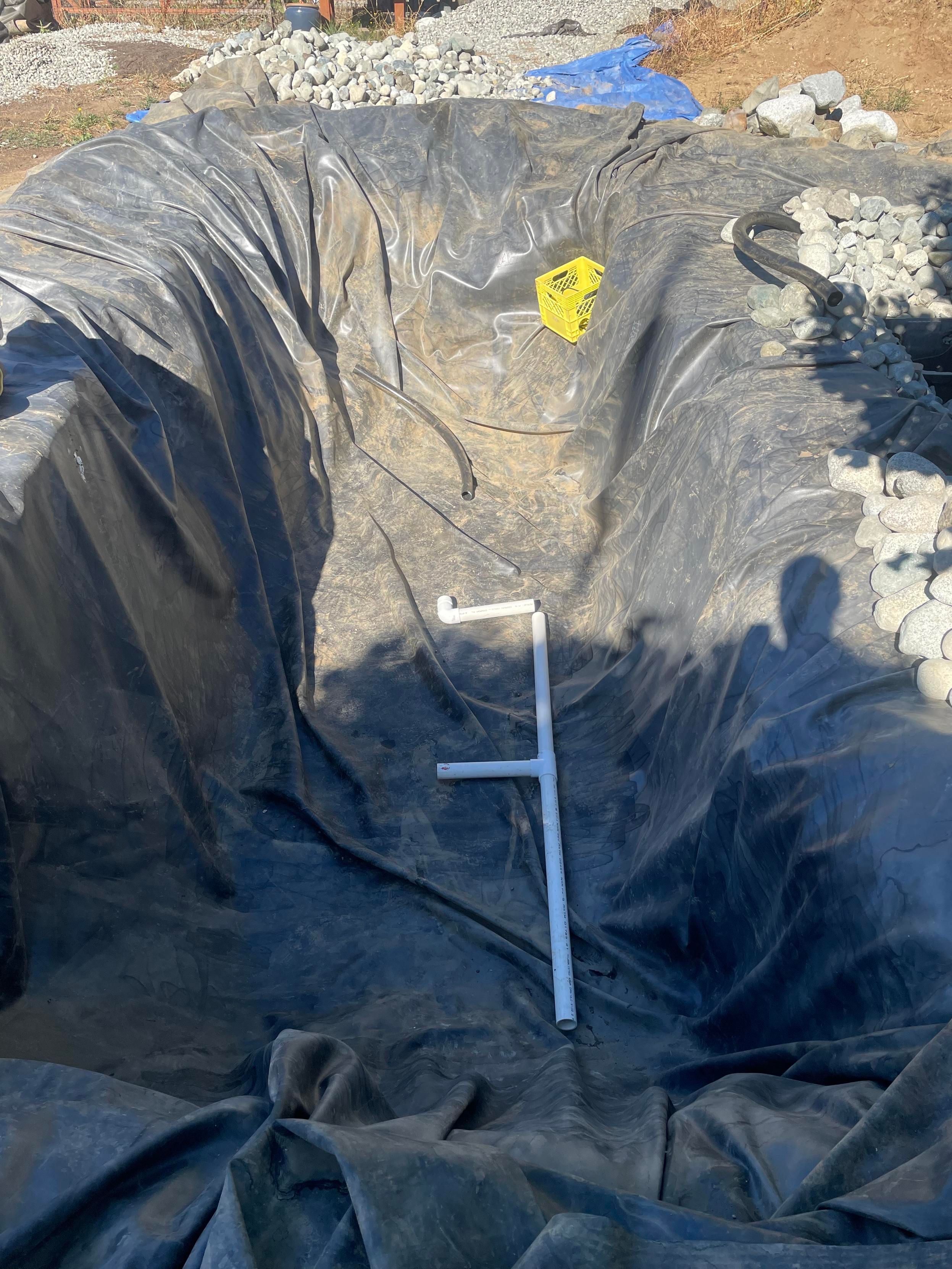 a picture of a sort of reverse E shape pvc pipe in the bottomof the runber lined pond.