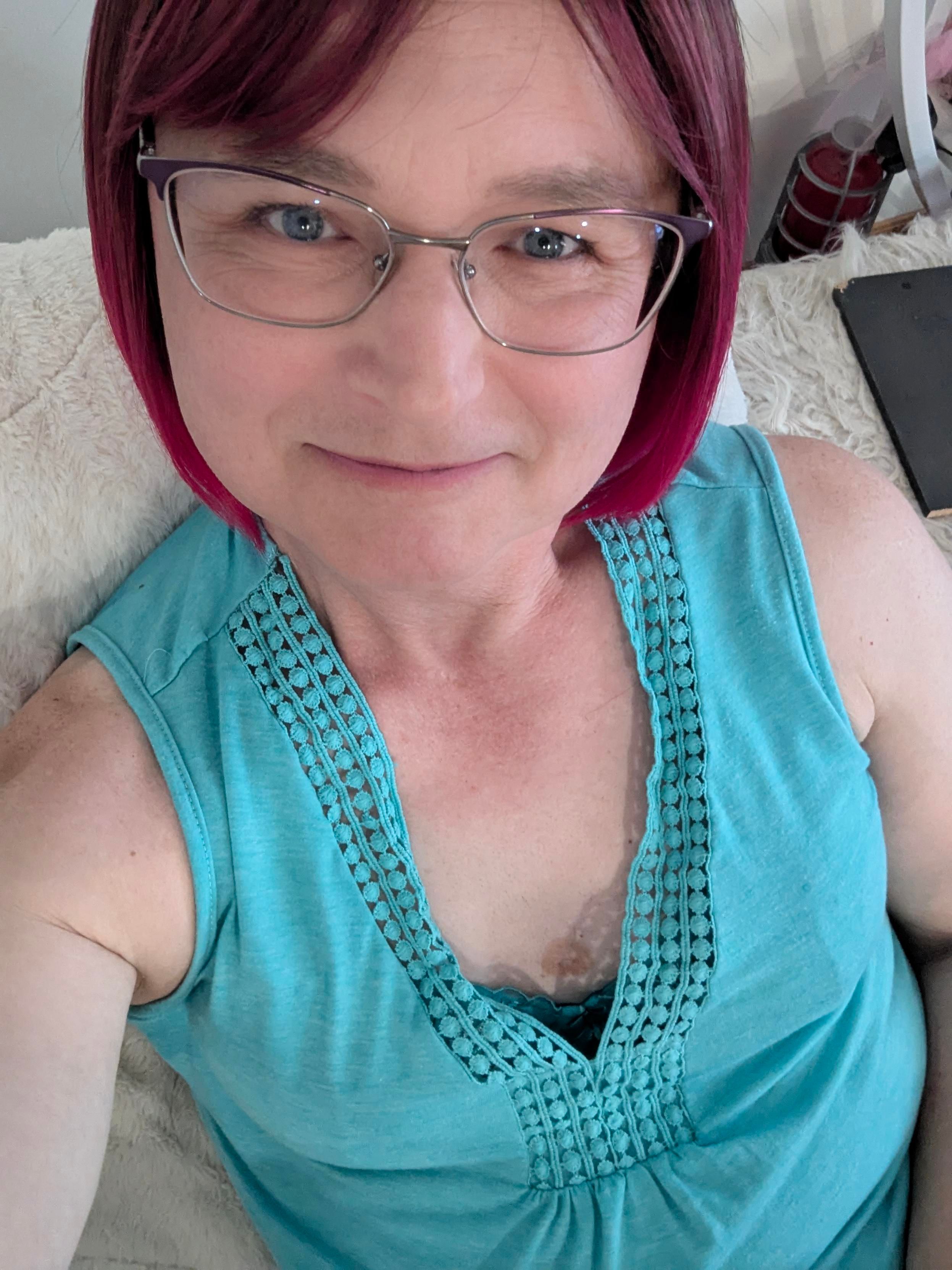 A selfie wearing my magenta wig and sleeveless turquoise top. Taken from an angle that shows my cleavage.