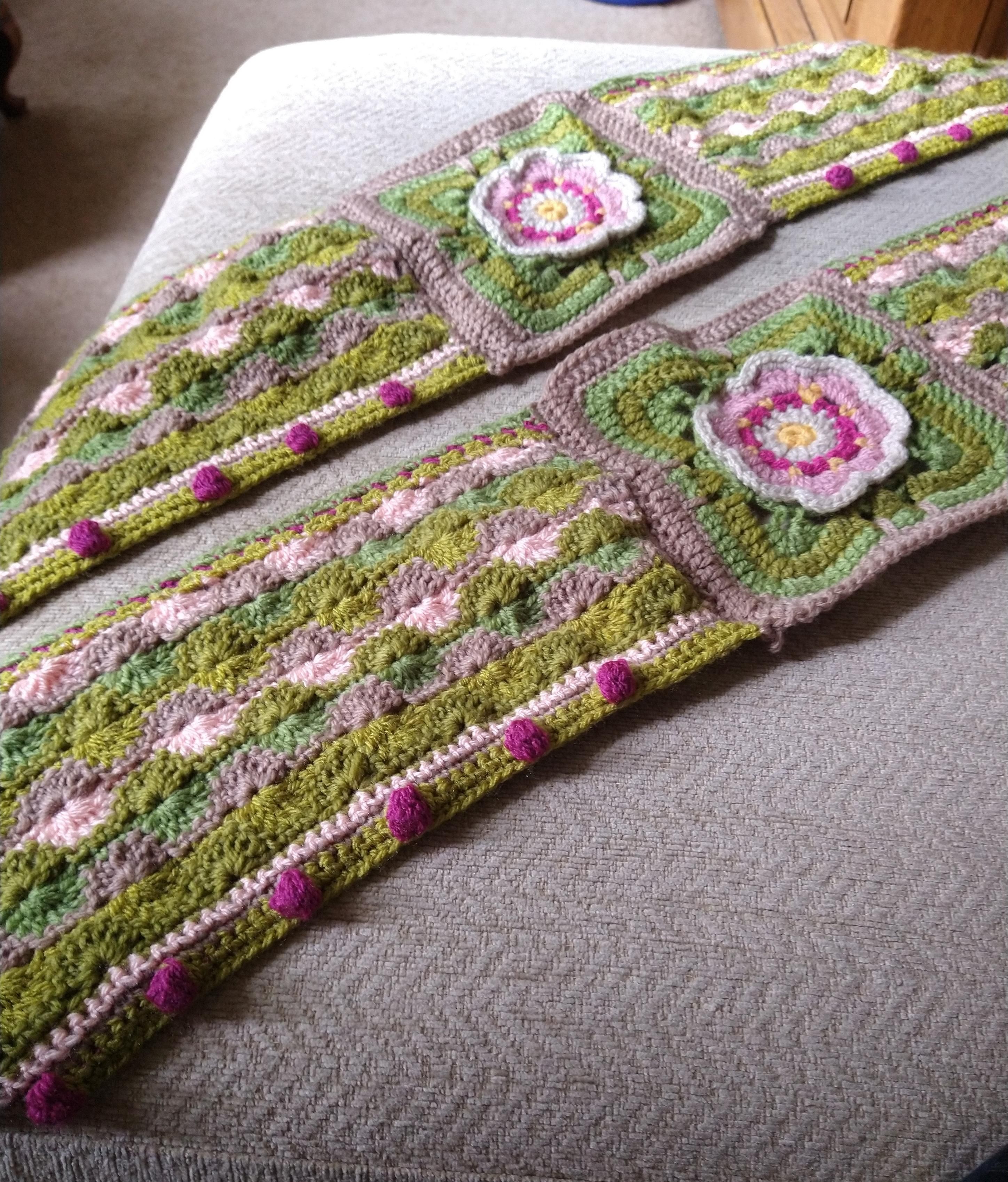 Two edge pieces of crochet pieced together from a central square with a flower middle, and a rectangle on either side 