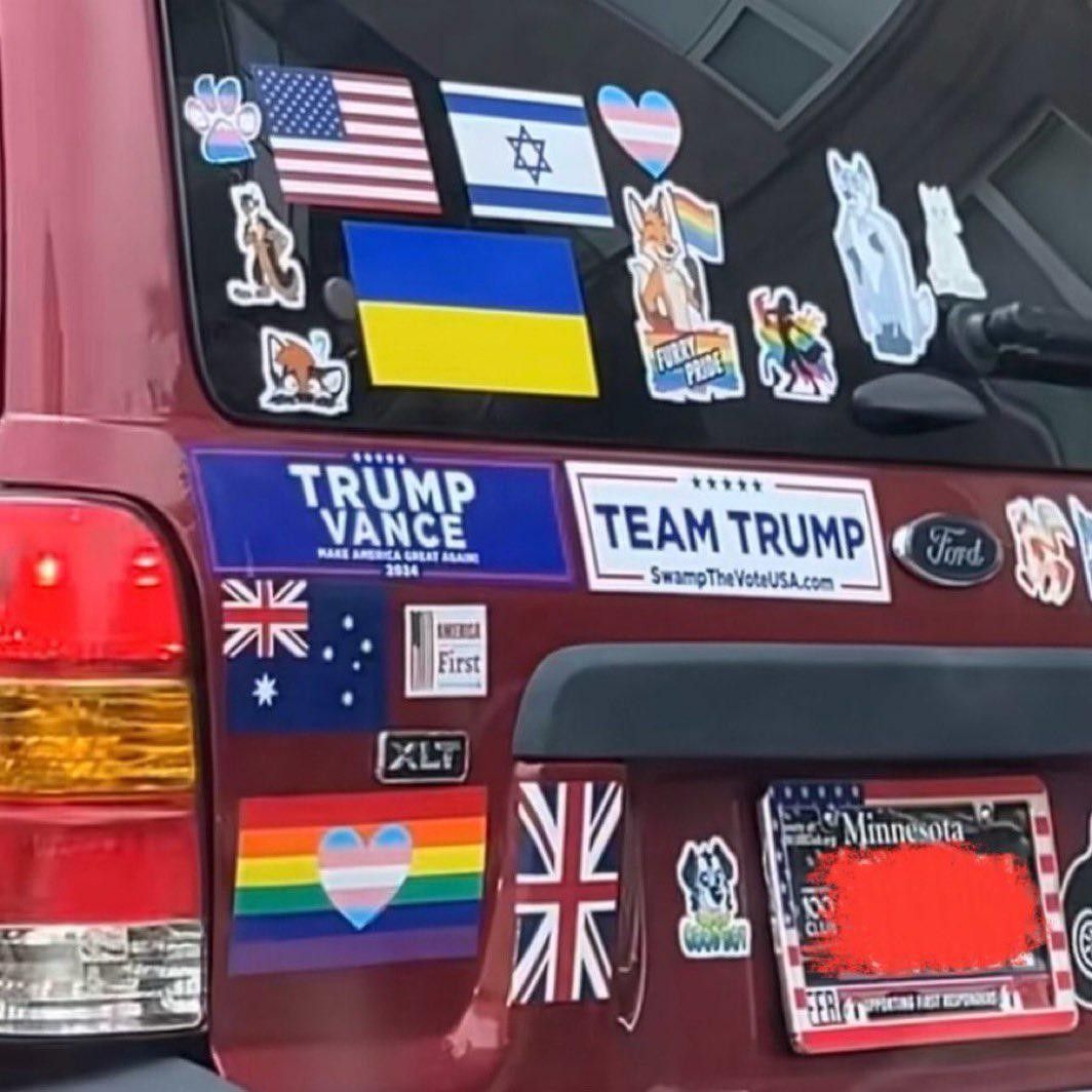 The back of a person's vehicle with many different stickers on it that don't seem to fit together. A "Trump / Vance" and a "Team Trump" sticker are surrounded by trans and furry stickers, U.S., Israel, Ukraine, and UK flags, America First, and more trans pride. 