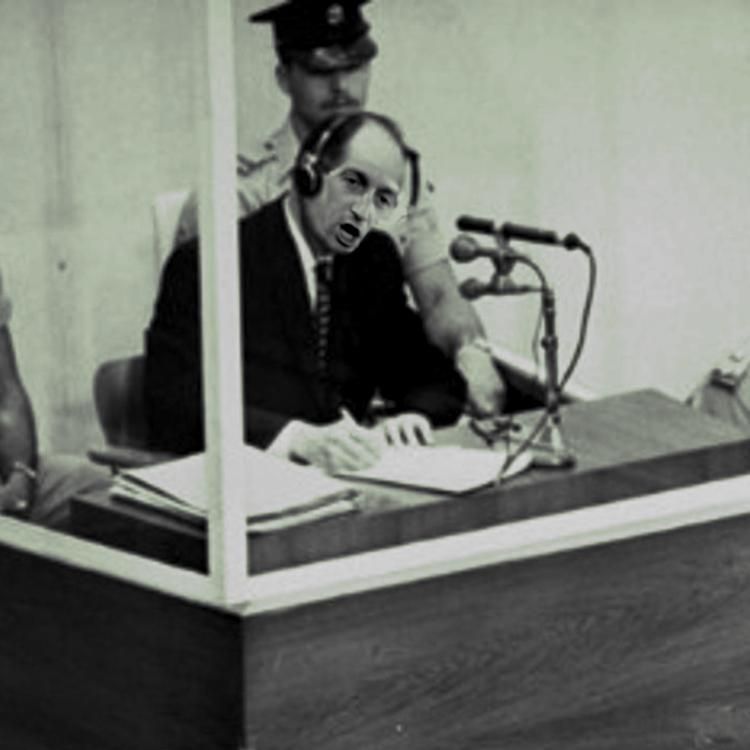 A famous 1961 photo of Adolf Eichmann on trial in Jerusalem; Eichmann's face has been replaced with the face of Stephen Miller.

Image:
Gage Skidmore
https://commons.wikimedia.org/wiki/File:2025_-_Stephen_Miller_(cropped).jpg

CC BY-SA 3.0
https://creativecommons.org/licenses/by-sa/3.0/deed.en