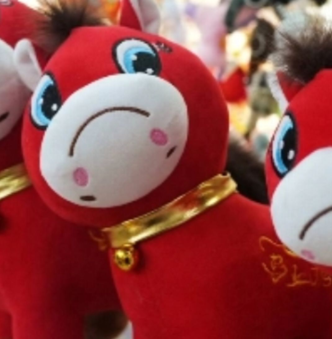 A close-up of the red, frowning, side-eye plushie horse