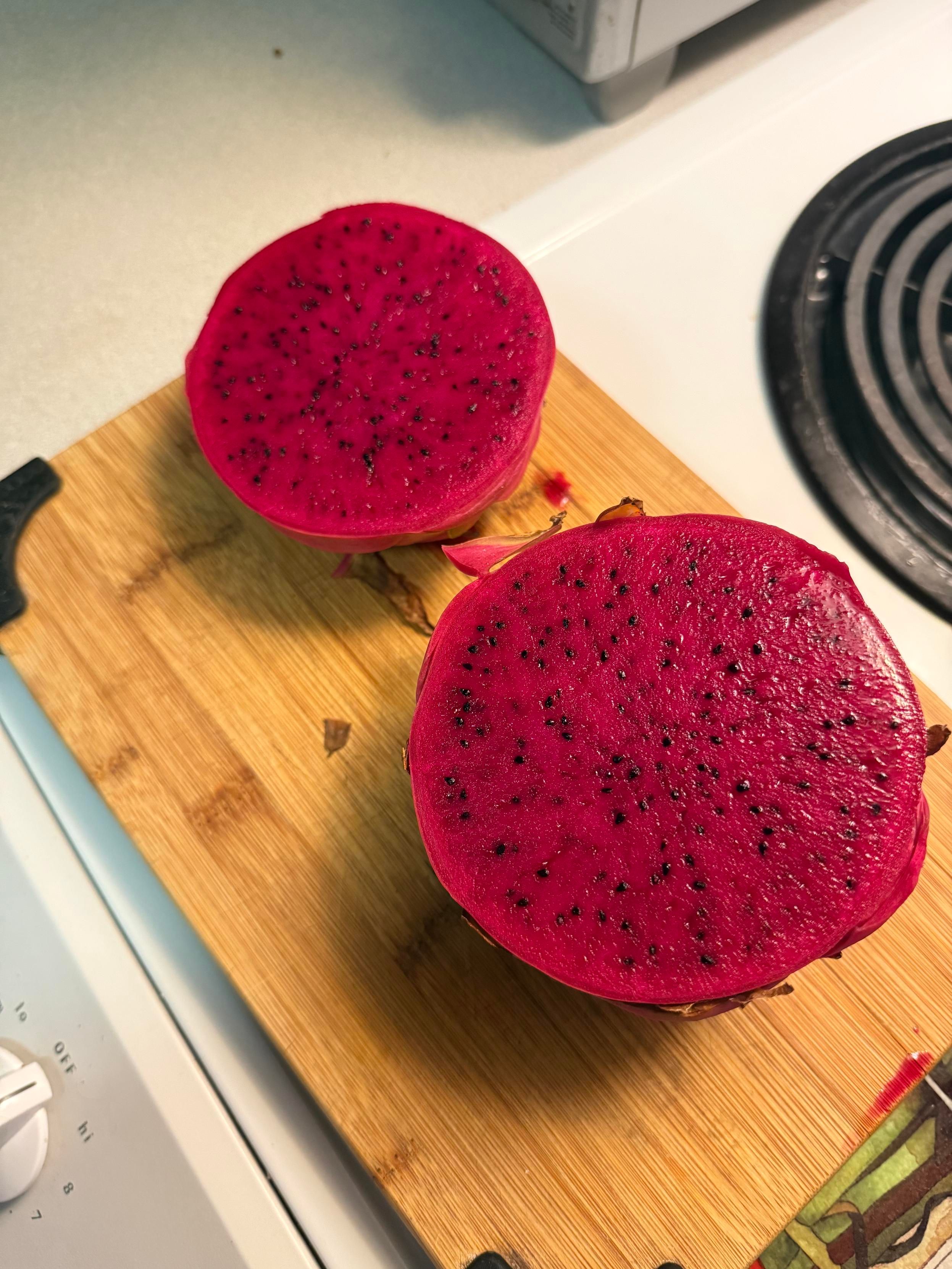 Halved dragonfruit with vermillion pulp and hundreds of tiny black seeds