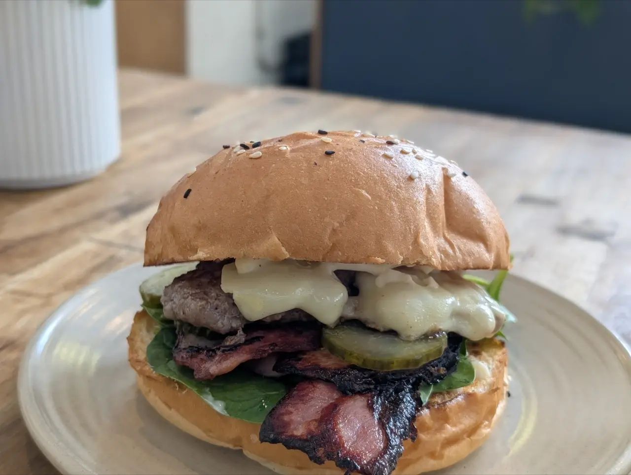 a hamburger with meat, bacon pickles spinach and cheese