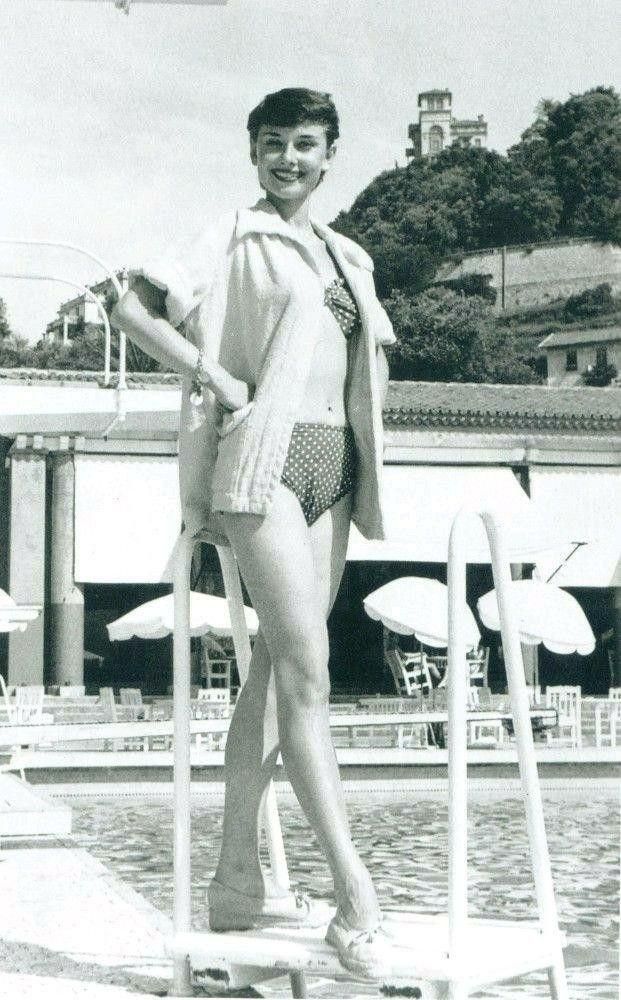 Audrey wears a sweater over a polka dot bikini as she poses poolside. 
