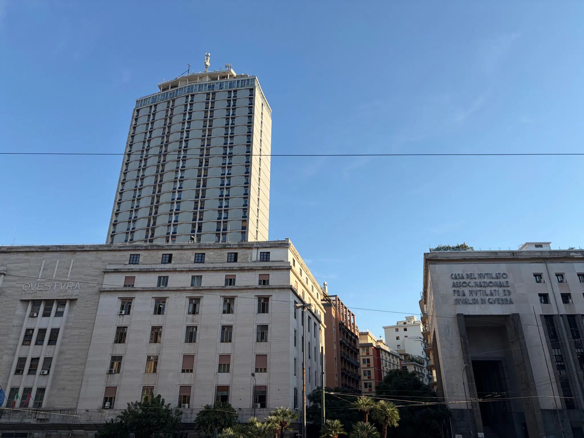 Foto dei palazzi di fronte, "QVESTURA" e
"CASA DEL MVTILATO
ASSOC. NAZIONALE
FRA MVTILATI ED
INVALIDI DI GVERRA"