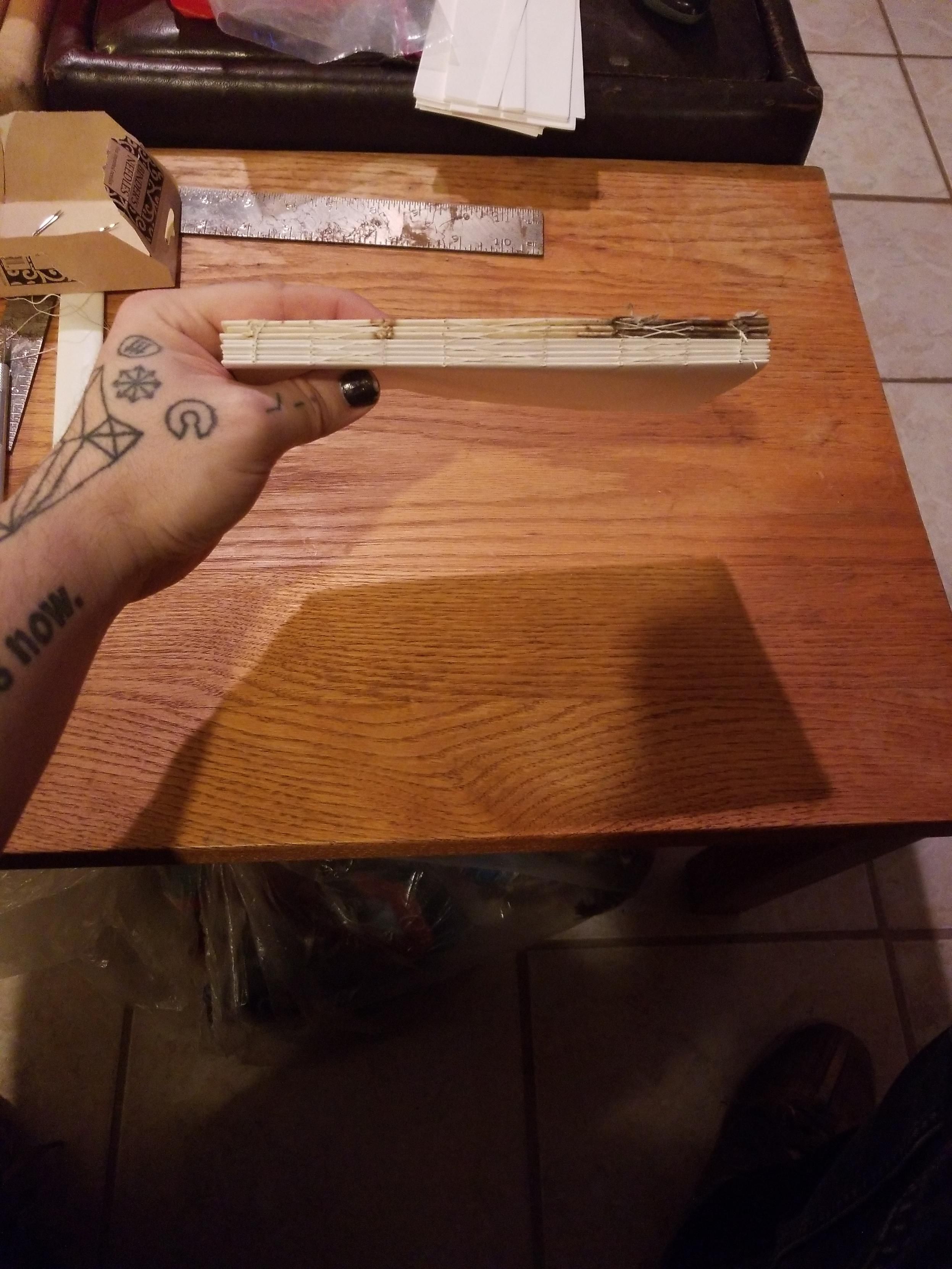 A collection of stitched signatures from the original journal with a stack of fresh signatures, stitched together and ready for binding