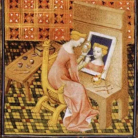 Giovanni Boccaccio’s De Mulieribus Claris (On Famous Women).

A woman is shown seated at a desk or writing table, engaged in what appears to be a scholarly or artistic activity. She is depicted in profile or three-quarter view, dressed in flowing robes of soft pink or coral color with golden blonde hair. Her posture and the positioning of her hands suggest she is either writing, painting, or examining a manuscript or mirror.

https://en.wikipedia.org/wiki/De_Mulieribus_Claris