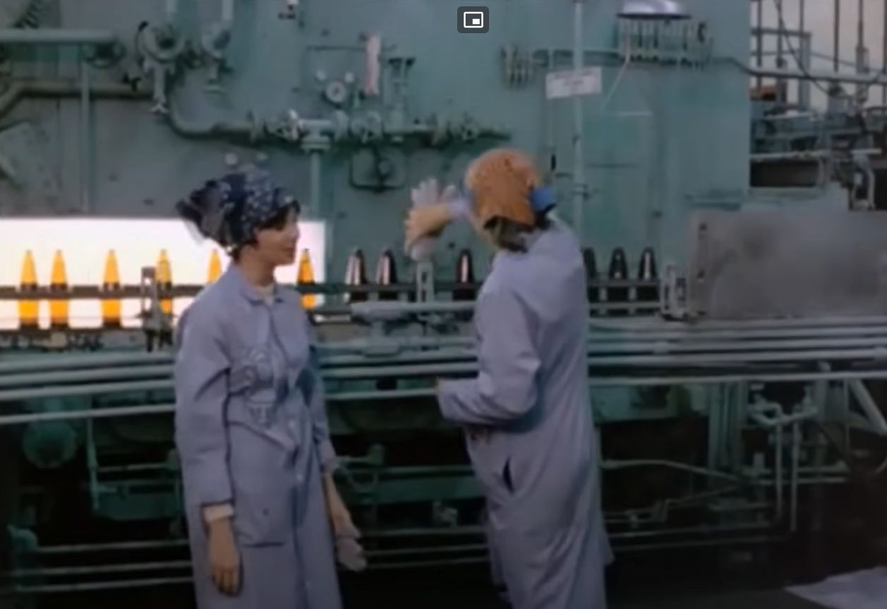 Screenshot (from the opening credits of) Laverne & Shirley (starring Penny Marshall and Cindy Williams) who worked quality control at Schotz brewery where they watched thousands of bottles of beer go by on the bottling line looking for ones that have dead rats in em.
In this shot Laverne blows up a rubber glove and puts it on one of the bottles as a hat. 