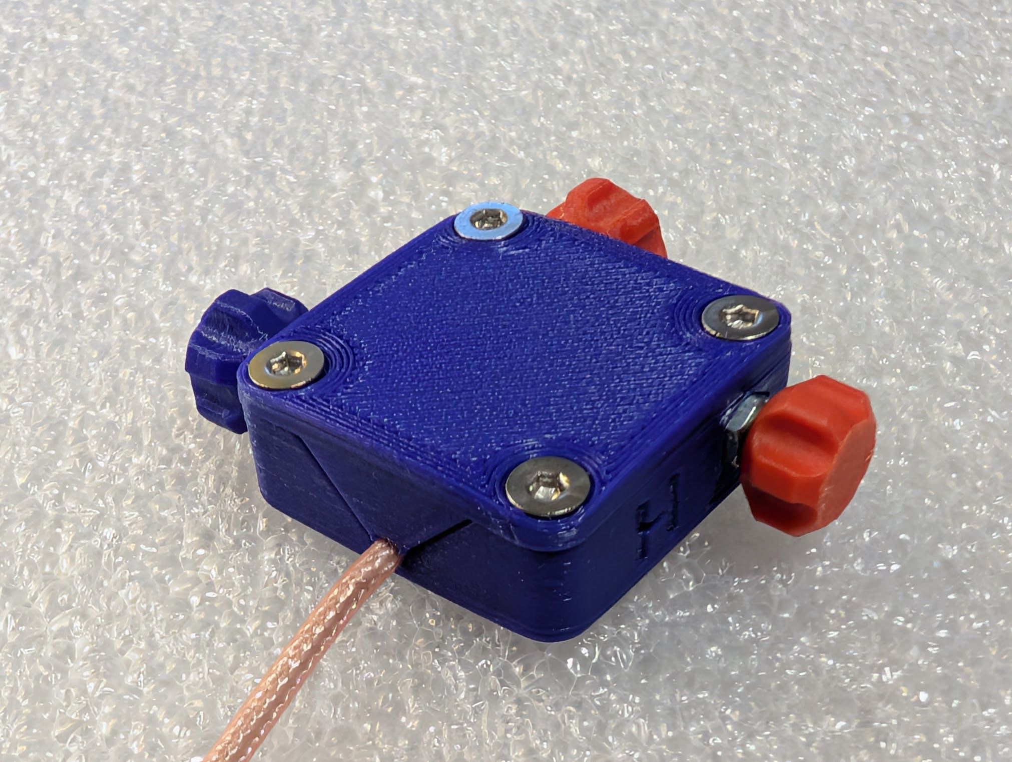 Lid installed on box, showing the tab capturing the RG316 coax where it exits the box.