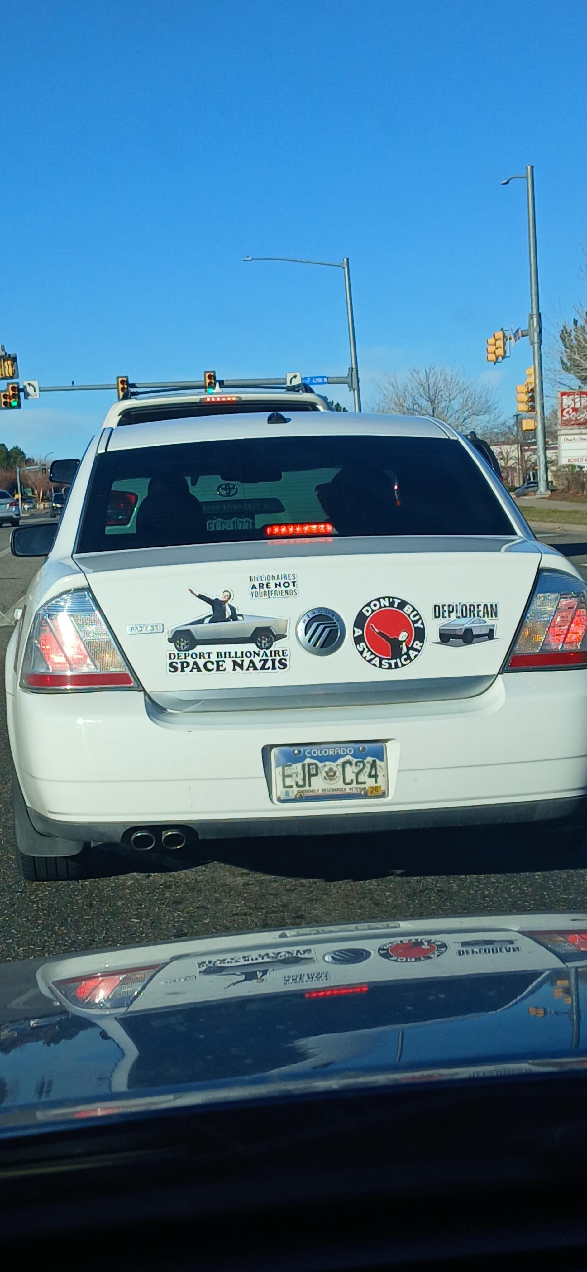 White car covered in anti musk bumper stickers 