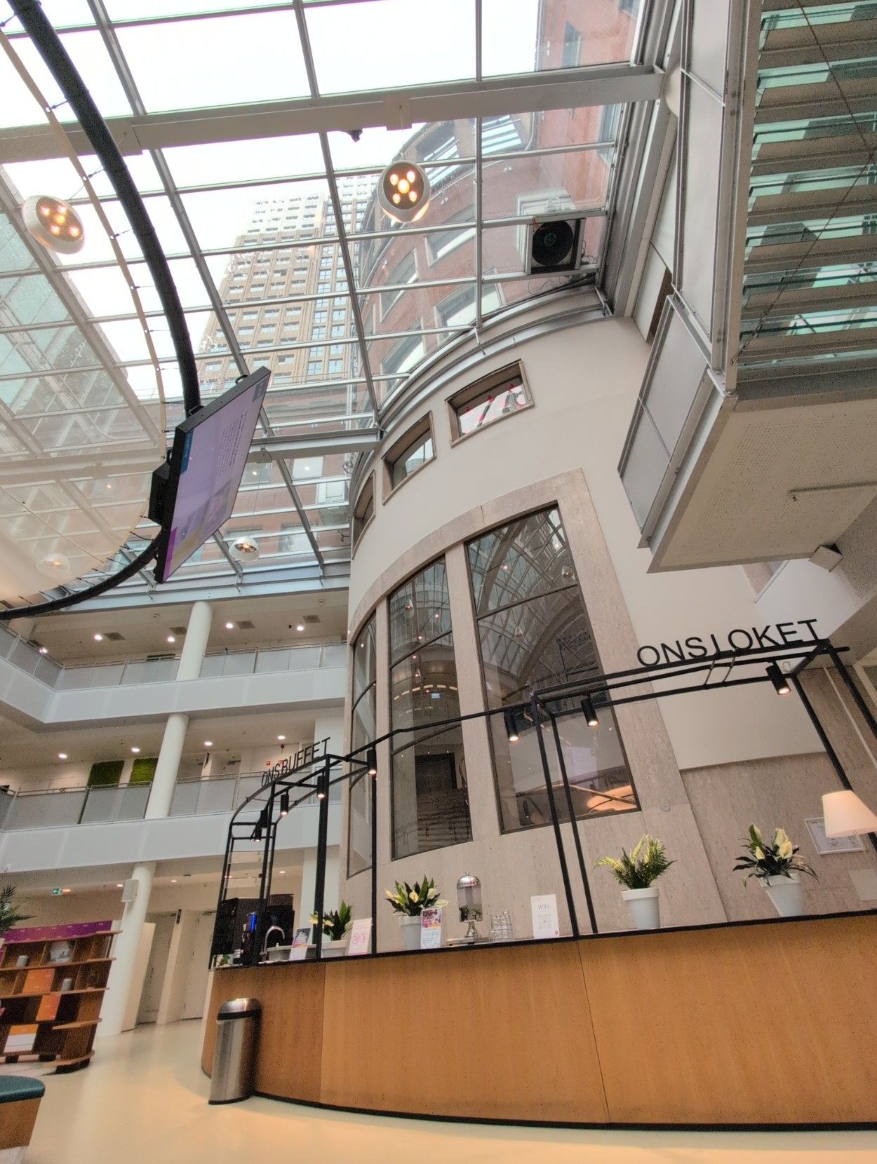 A photo of the inside looking upwards through the glass ceiling. The building in the back are Deloitte offices.