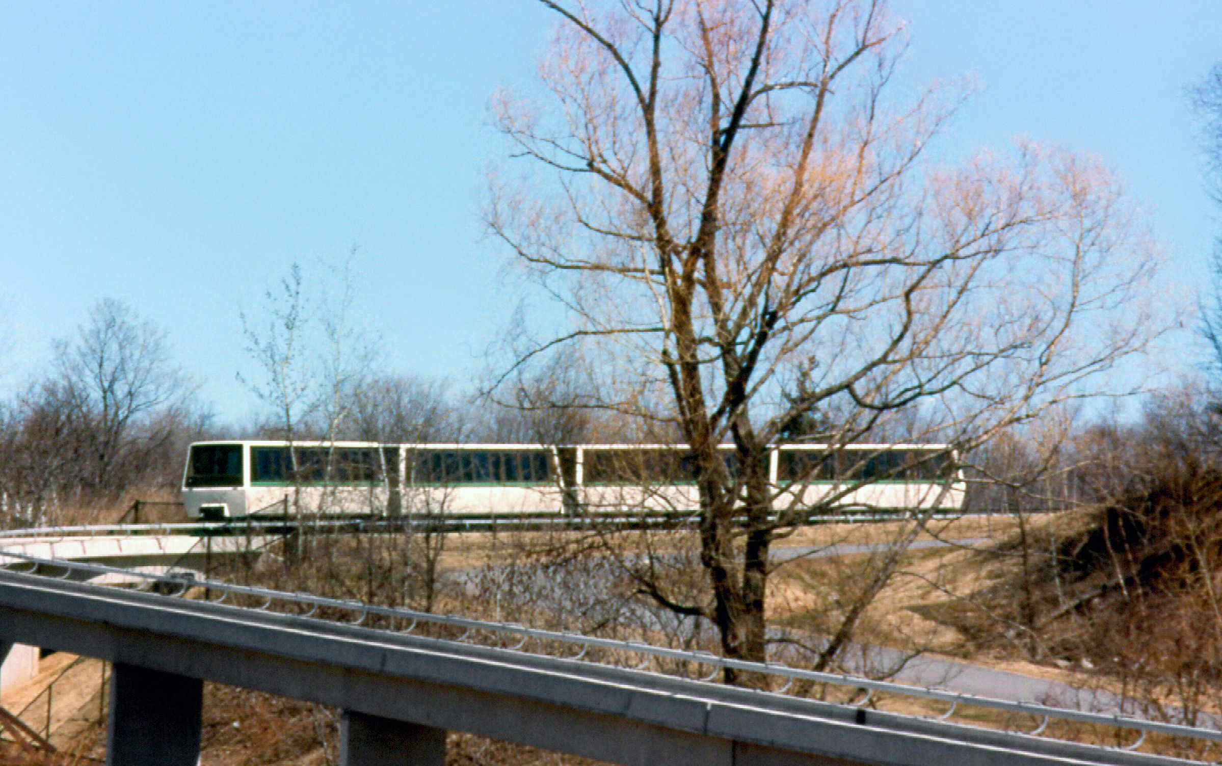 Photo from 1977 where we see the Toronto Monorail on an elevated concrete rail going through nature and forest in the winter