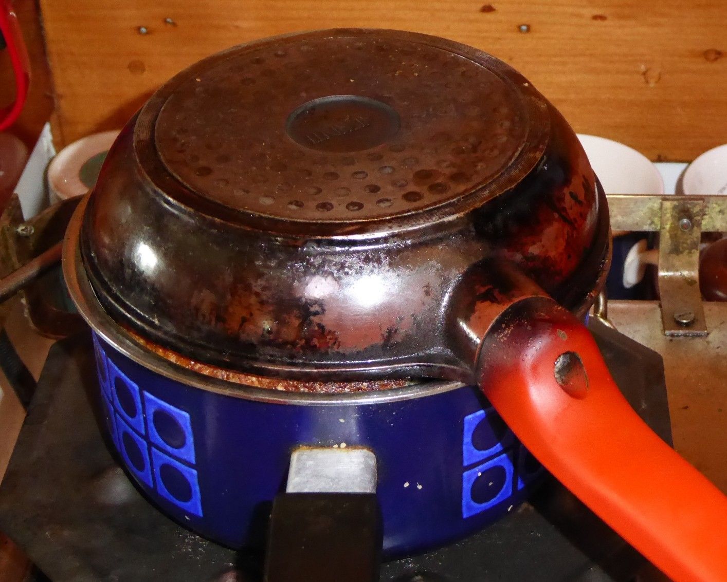 bread baked in a sauce pan, with a frying pan laying overtop. The saucepan is sitting over a flame tamer to spread the flame better on an LPG stovetop.