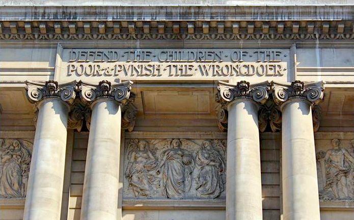 Defend the children of the poor & punish the wrongdoer, carved into the front of a large stone building with four columns