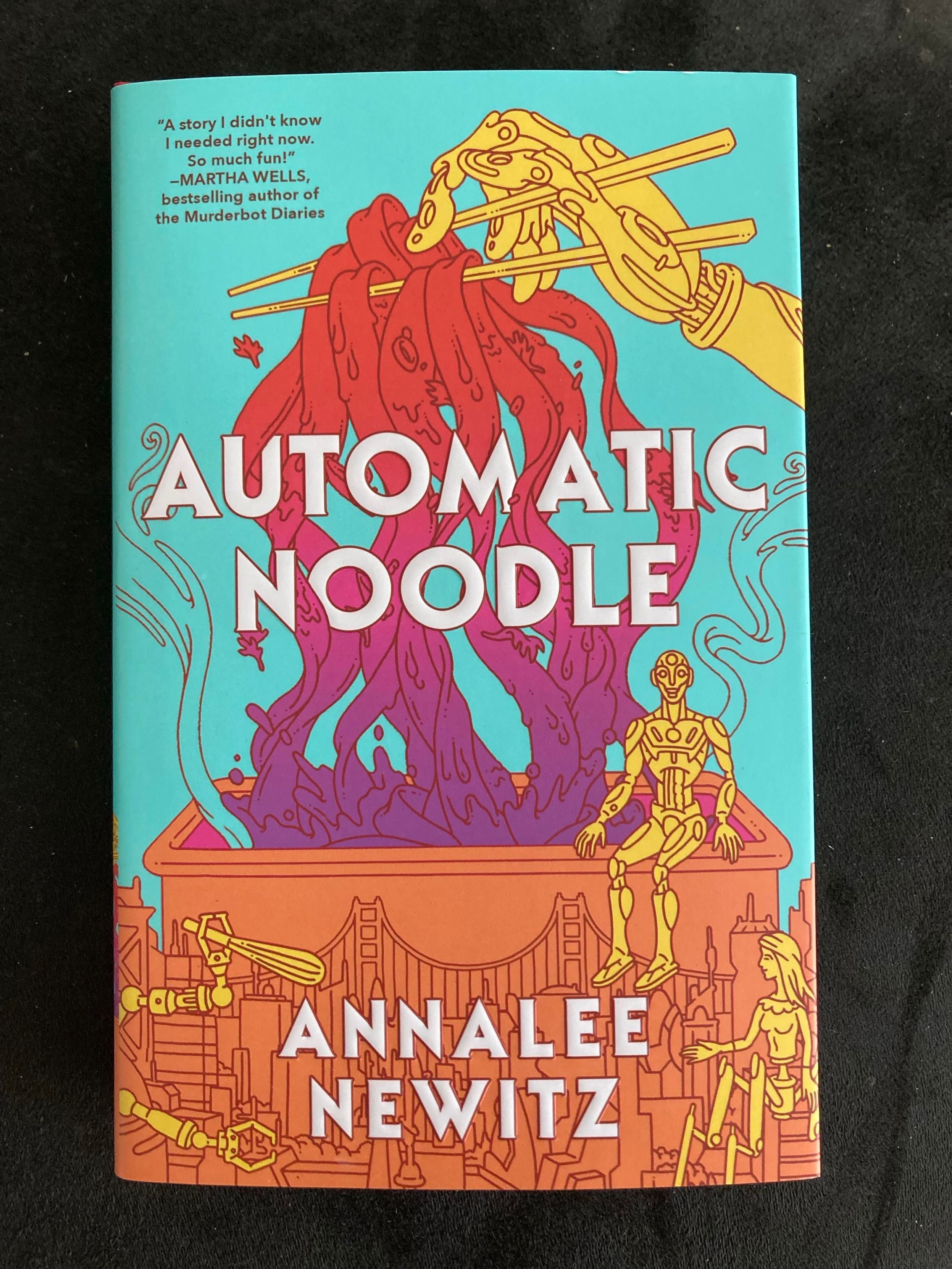 A photo of the dust jacket of a new novel titled Automatic Noodle. The cover shows several yellow robots preparing and eating a giant bowl of red noodles.