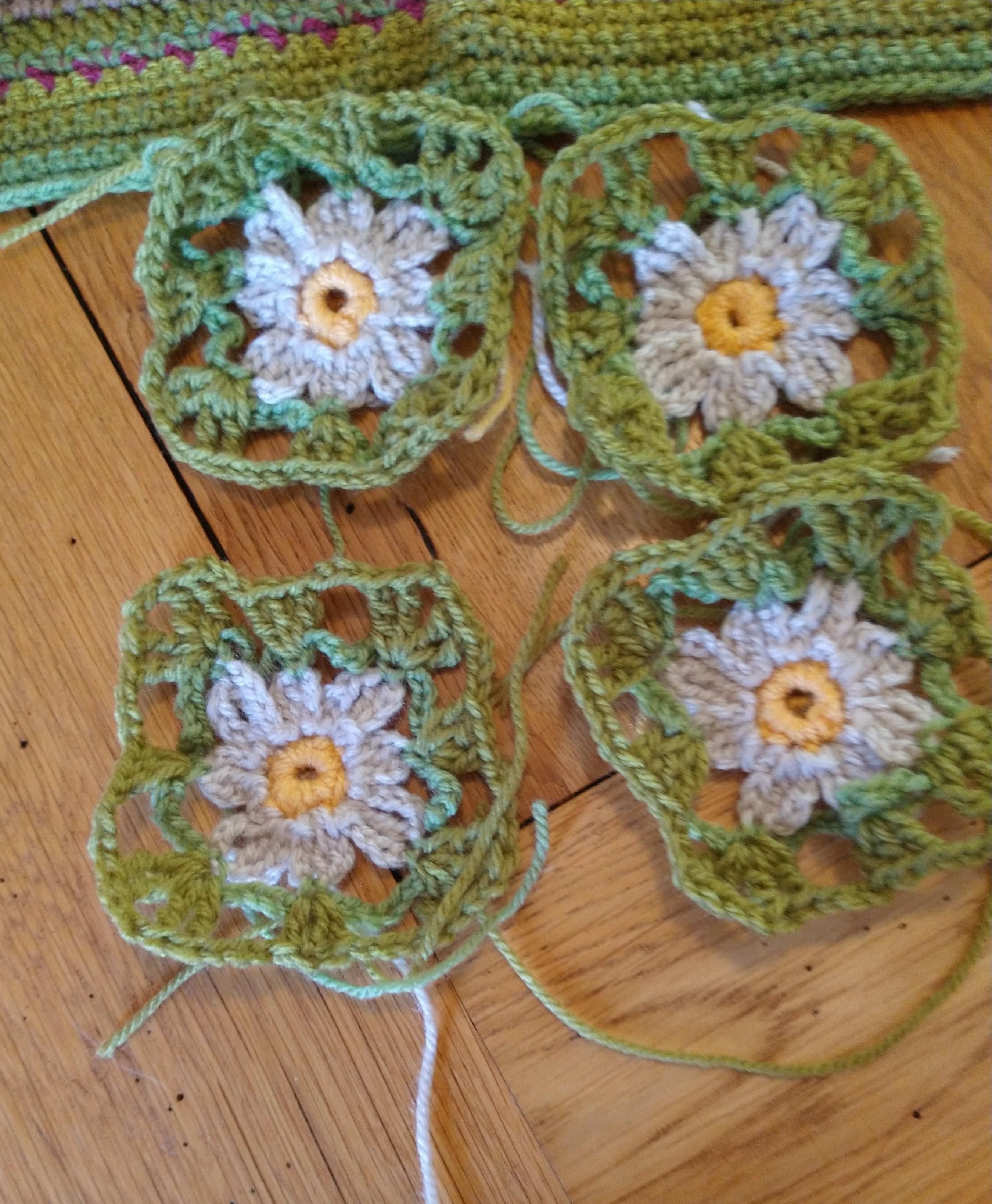 Four small crochet squares with yellow centres and green borders to look a little like daffodils 