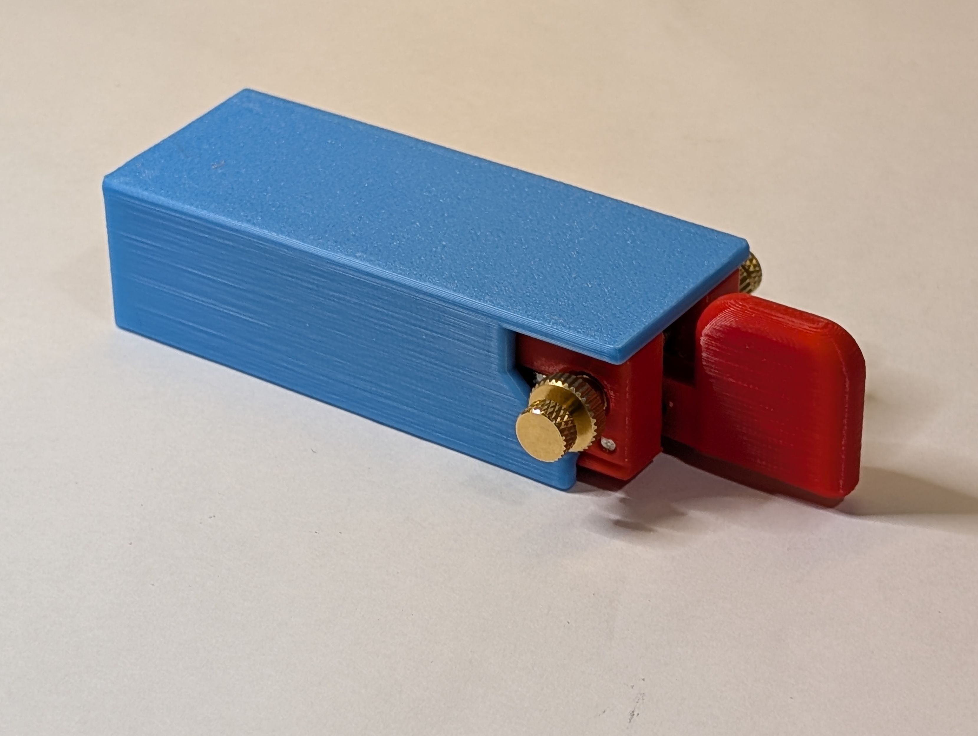 Morse code key inserted into a handle for easier keying. The Morse code key is red, the hardware is brass, and the handle is blue.