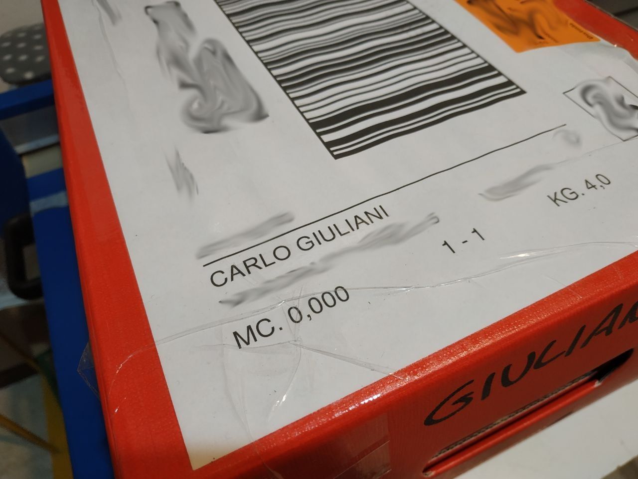 Foto di un pacco rosso con etichetta bianca il cui nome del destinatario è Carlo Giuliani.