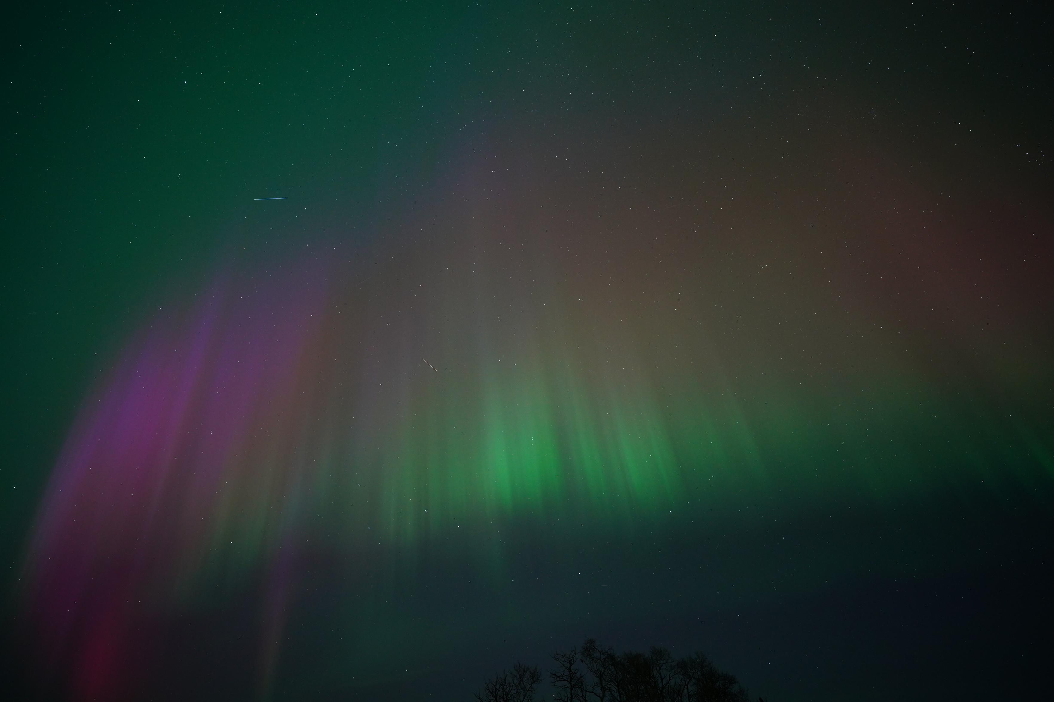 An arc made of vertical columns starting green at the bottom, transitioning to orange and then red then purple at the top, with green in the background of the sky.