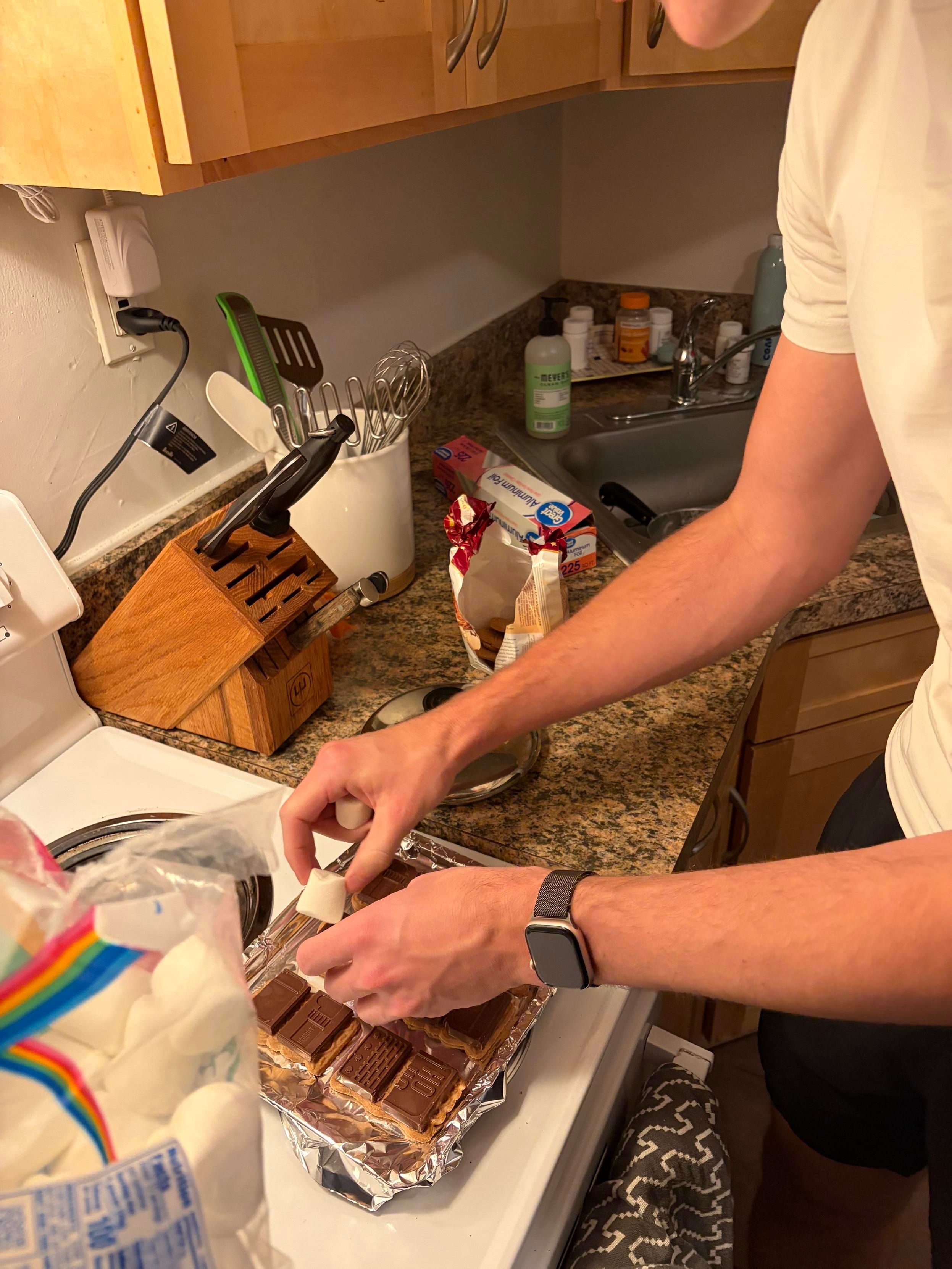 assembling the s’mores, placing marshmallows on the chocolate on the cookies