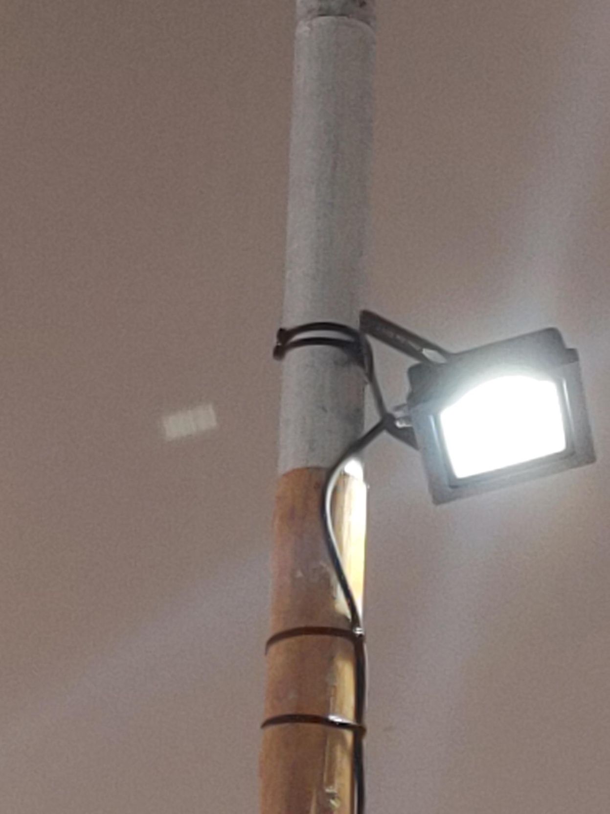 A light rigged to a pole with a pair of cable ties