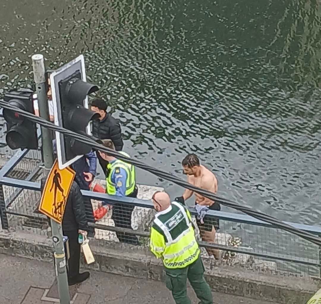 Photo showing a shirtless Muhammad - a Moroccan immigrant in Cork City, Ireland, being helped out of the River Lee by local Gardaí after he jumped in the river to successfully rescue a woman who had fallen in. 
