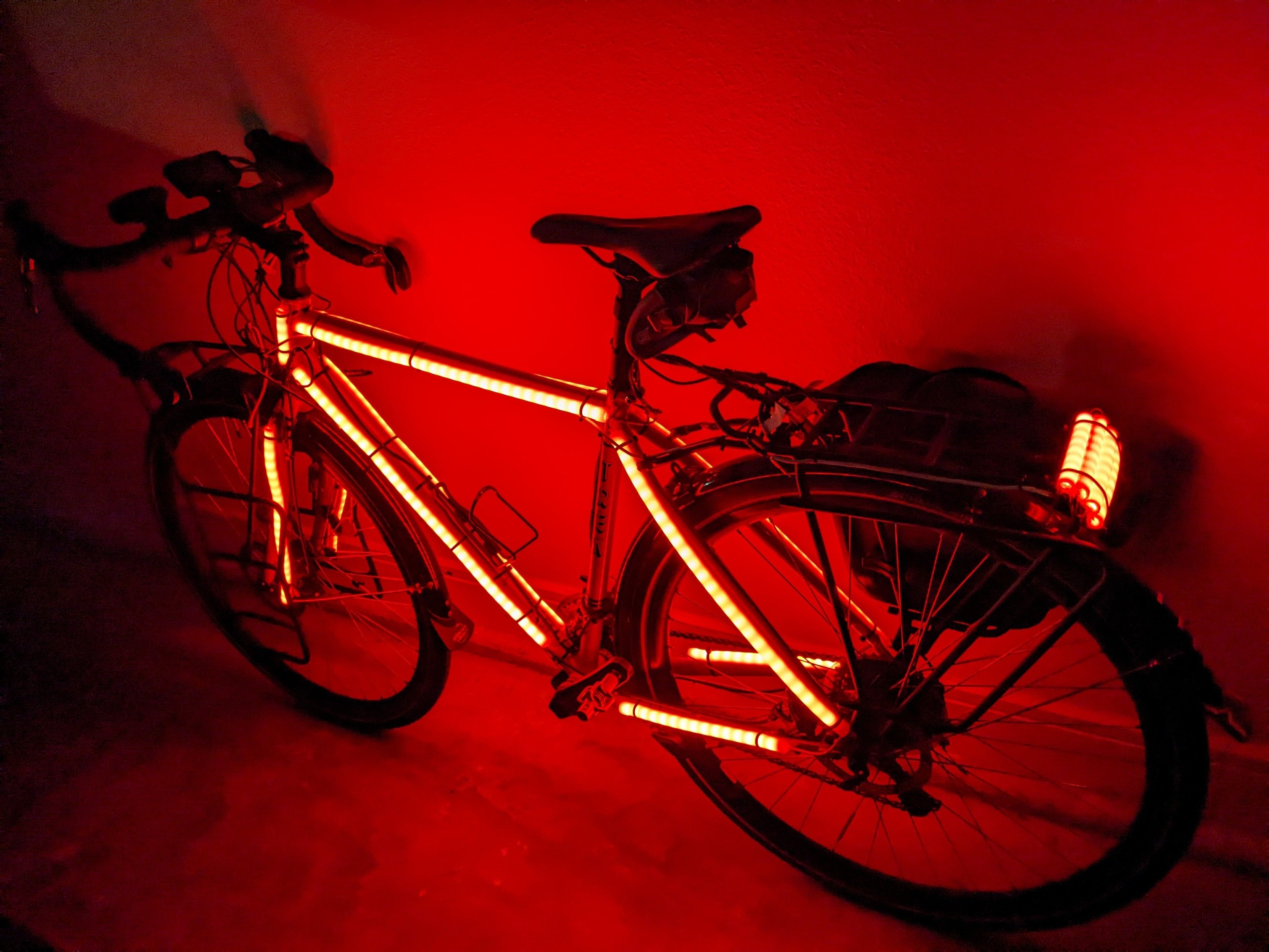 Side view of bike with red LEDs on the side of the frame & fork and a stack of three rows of LEDs molded to the rear pannier frame