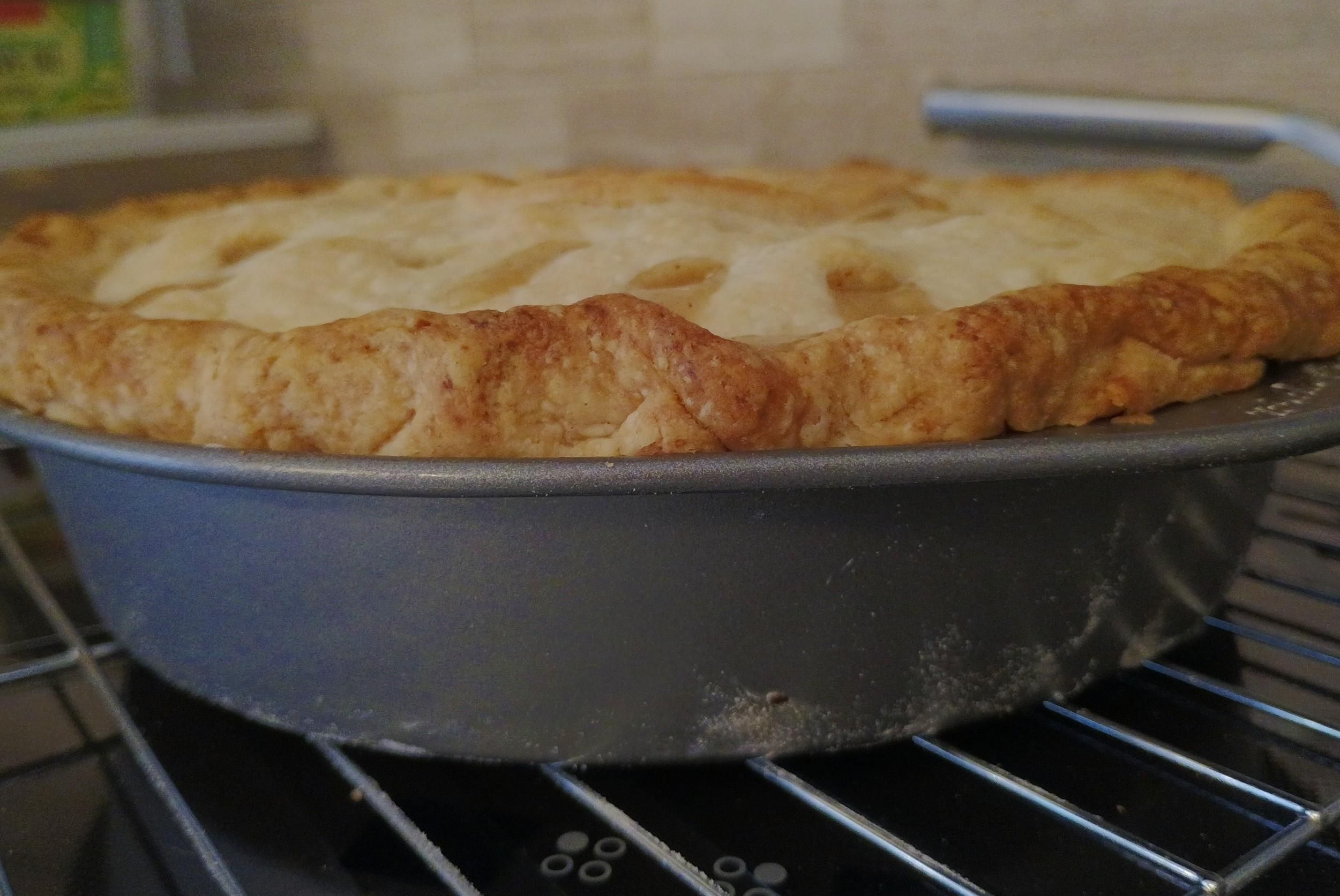 A side view of a cake pan with a golden bit of pie crust above it
