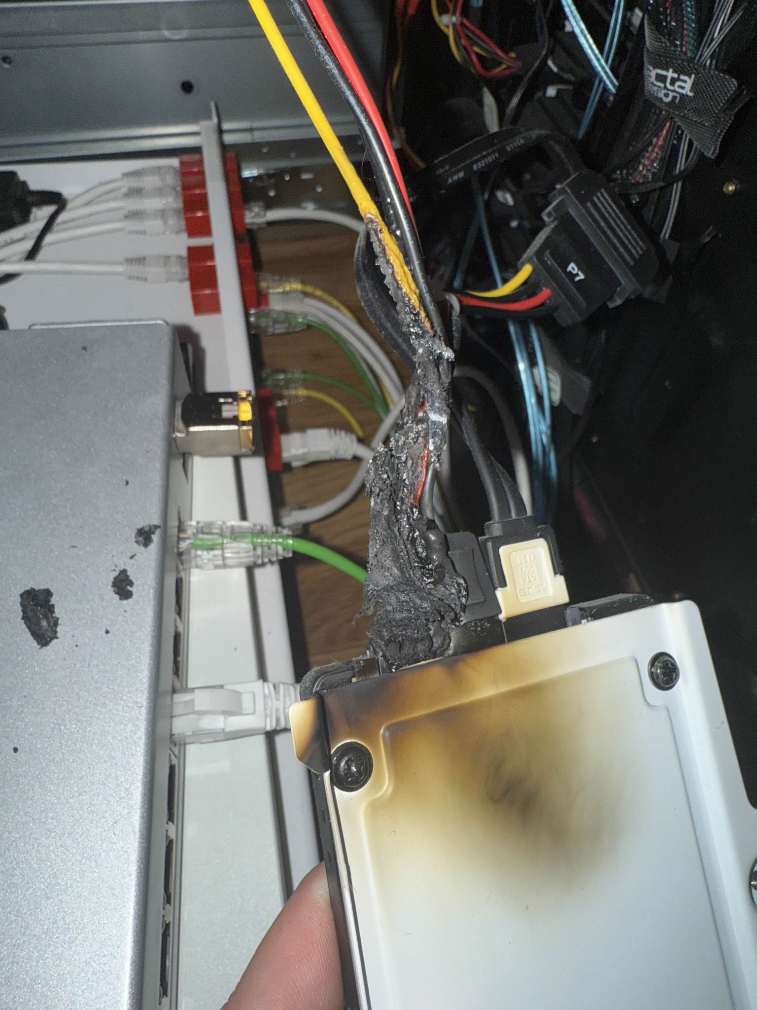 the backside of said drive, the white disk caddy is full of soot and has yellowed

The cable sticking out of it is severly melted and in the background several crumbs of burnt plastic can be seen lying on the table