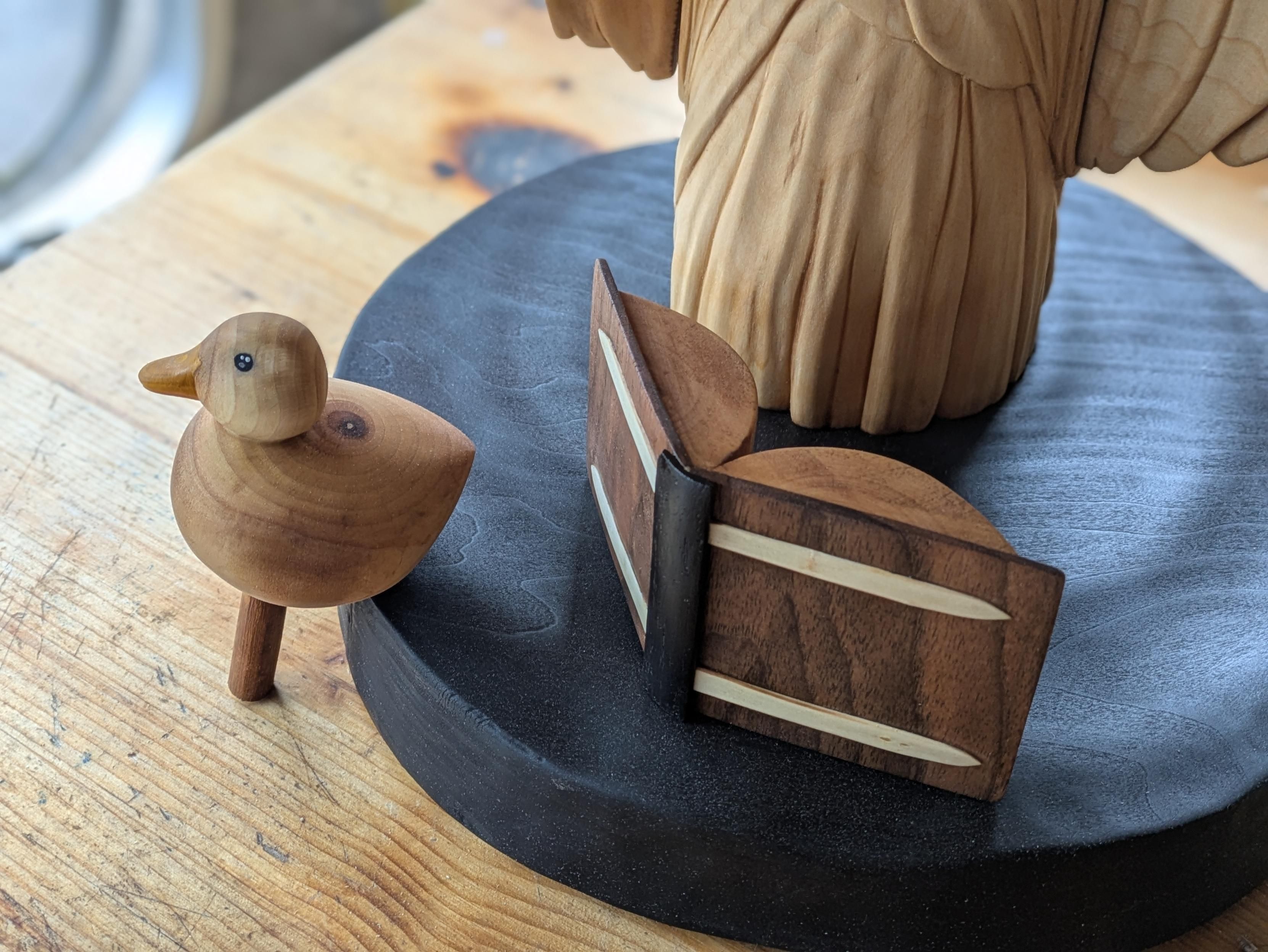 A woodcarved duck, a open book on a burnt base representing water, and the bottom of a dress (wich is a part of a humanoid ocotopus)