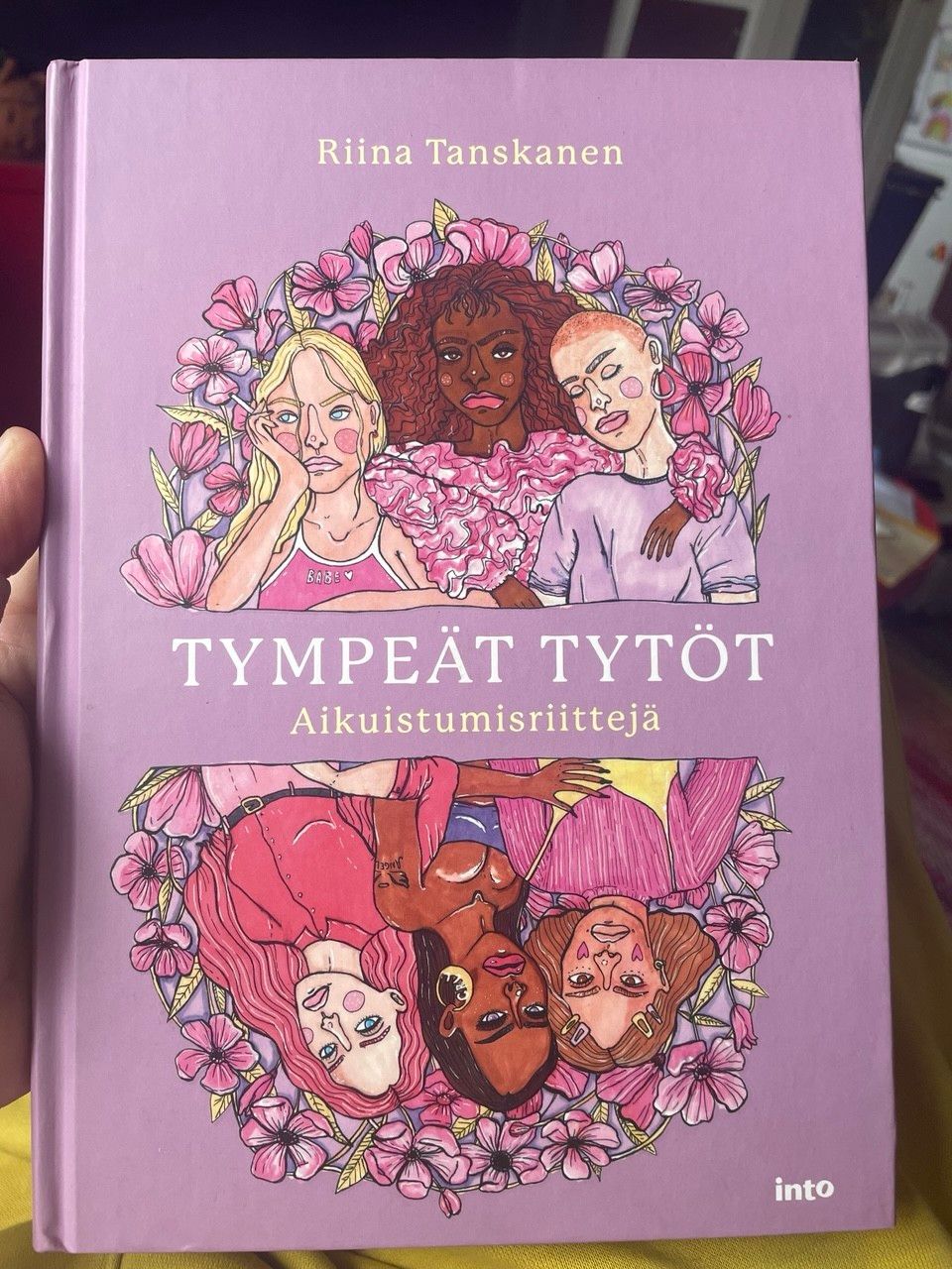 Tympeät tytöt etukansi. Erilaisia tyttöjä tyylitellysti piirrettyinä kukkasien keskellä.