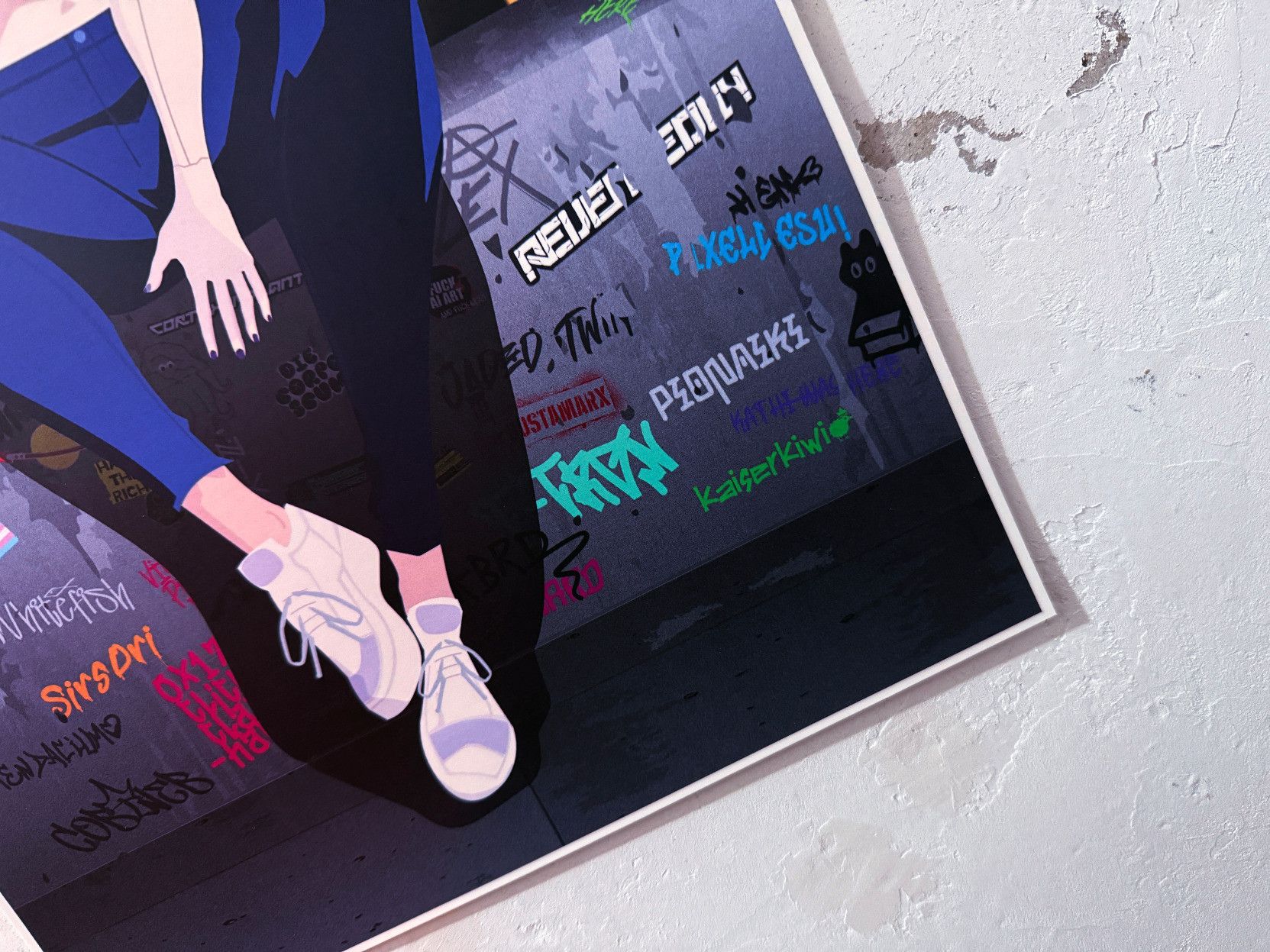 The image shows a section of an animated figure, focusing on the lower legs and feet of a character wearing white sneakers and blue clothing. The character is against a wall covered with colorful graffiti text and symbols.