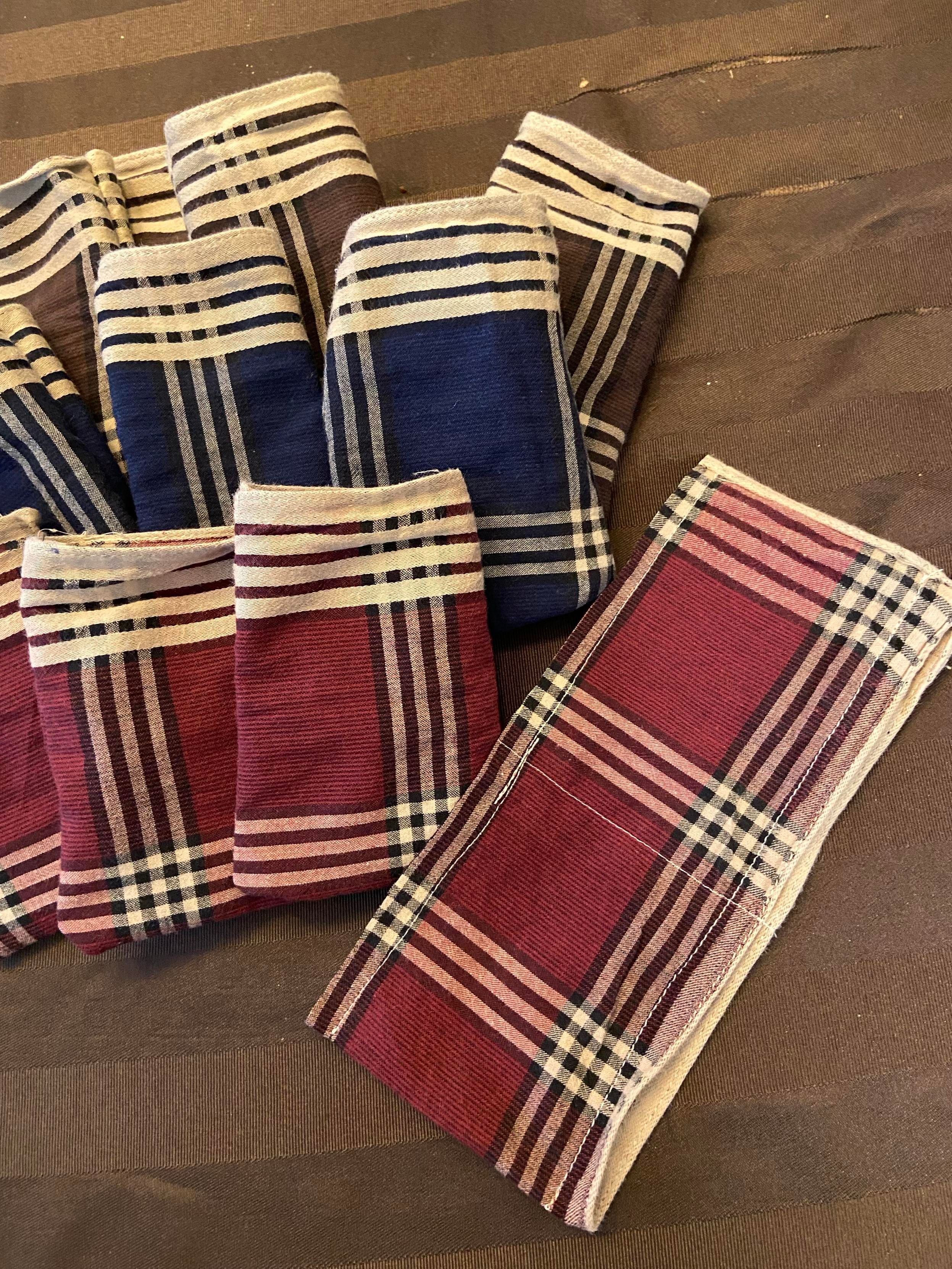 One sewn fabric bag that is still inside out, with a lot of excess fabric at the bottom, next to several bags that have been turned right side out. 