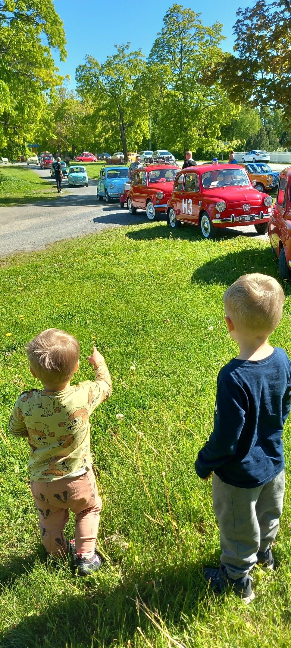 Two toddlers looking at old cars.