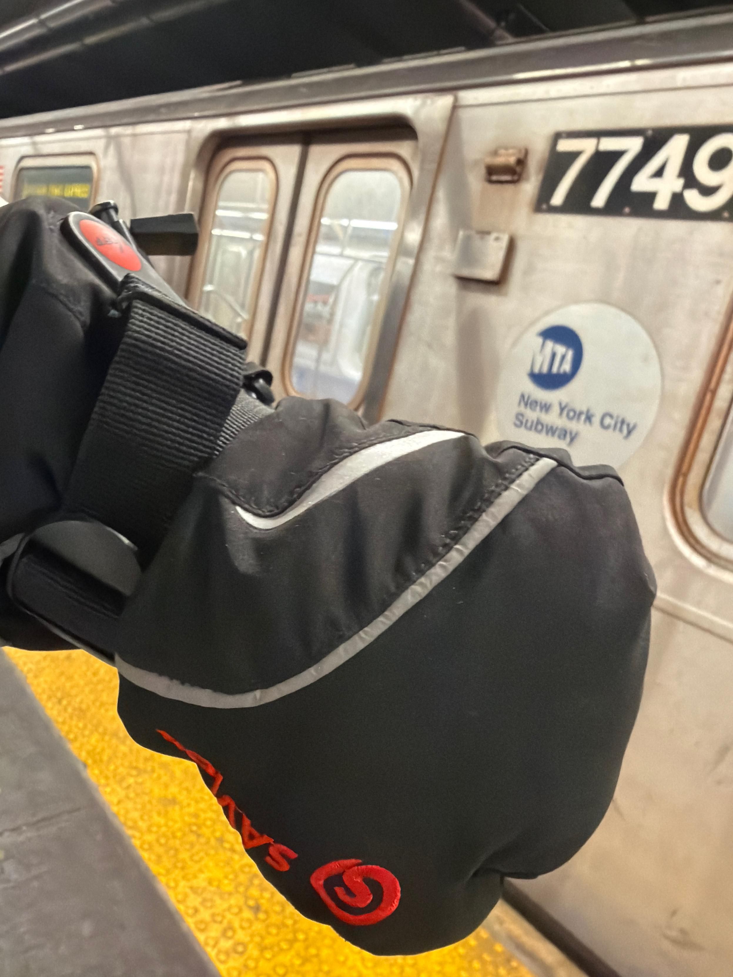 One of my big heated mittens a black glove designed for attic conditions being used in the subway 
