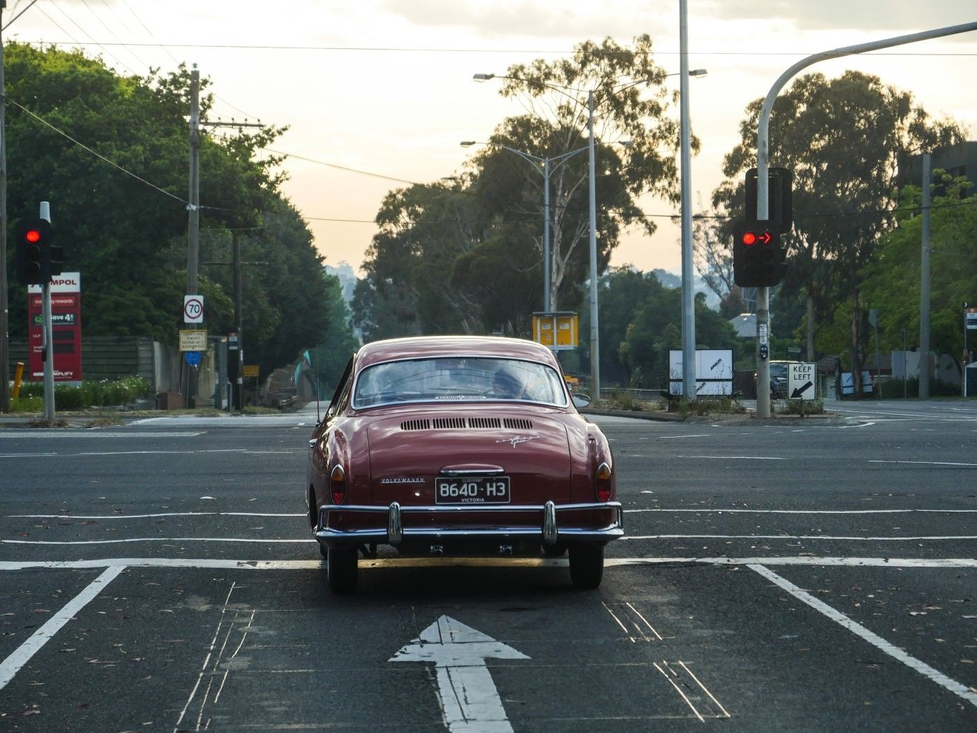A red Karmann Ghia is stopped at an intersection.